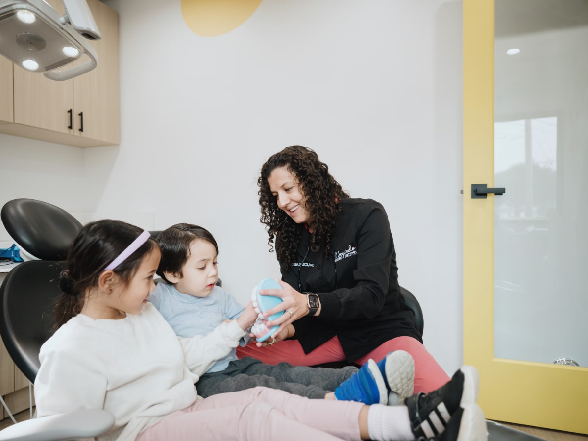 Pediatric dentist examining a young child in the dental chair with supportive care