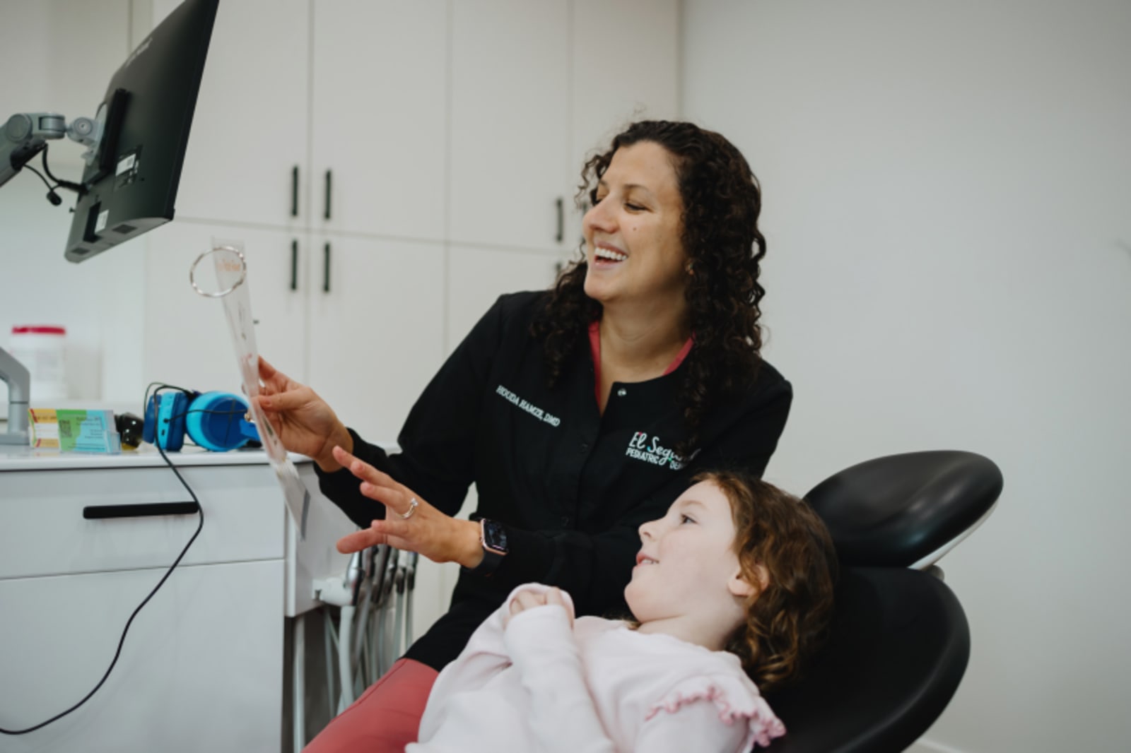 Dentist showing digital tablet to child patient while explaining dental procedure