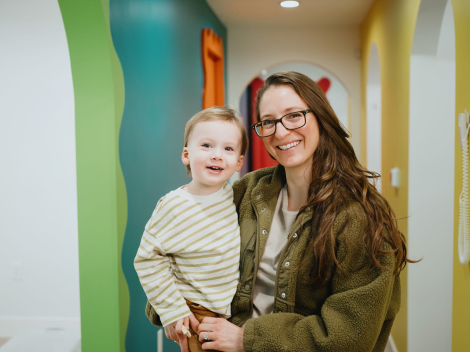 Dentist and caregiver smiling with child patient in welcoming office environment