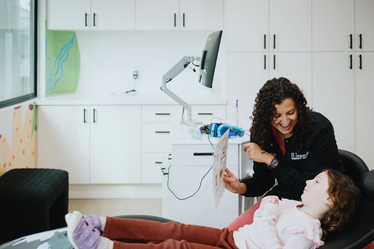 Pediatric dentist examining a young child in the dental chair during treatment