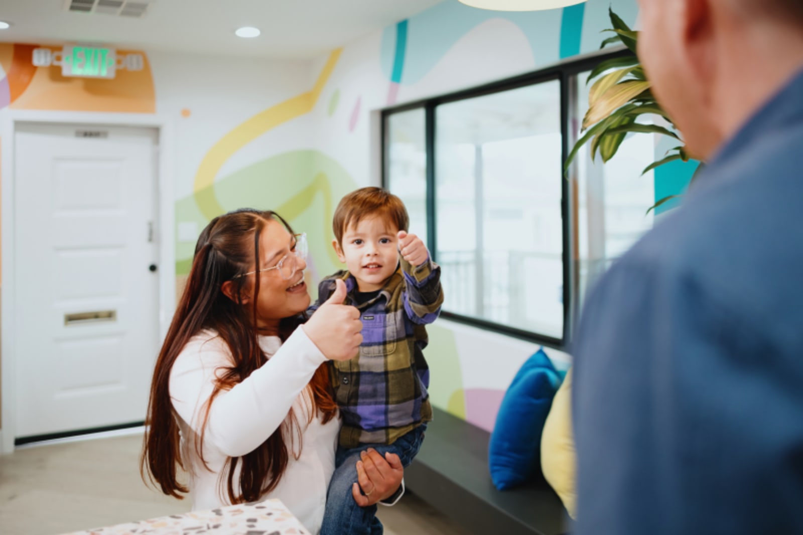 Pediatric dentist greeting and welcoming a child patient with parent at office entrance