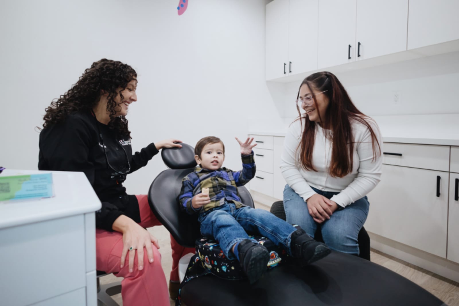 Dentist and assistant preparing a child for a dental procedure in treatment room