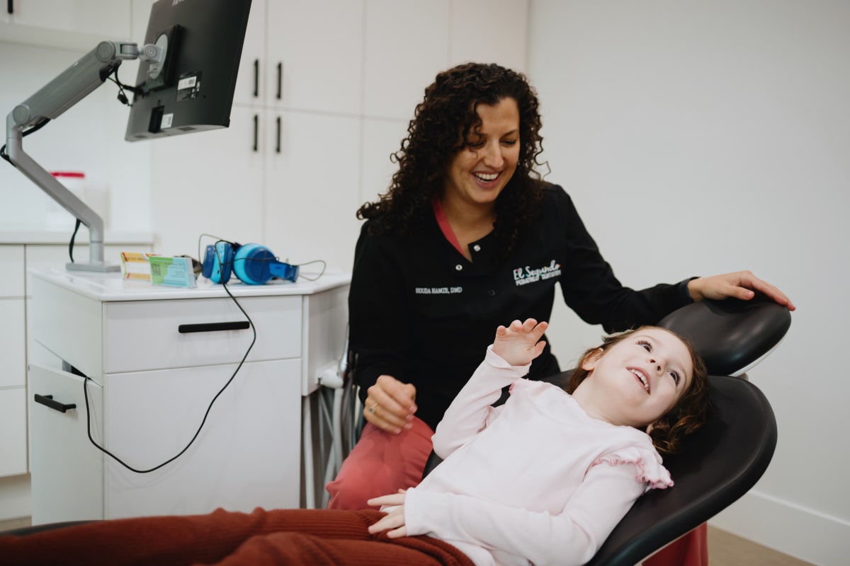 Pediatric dentist examining a young patient in the dental chair during treatment