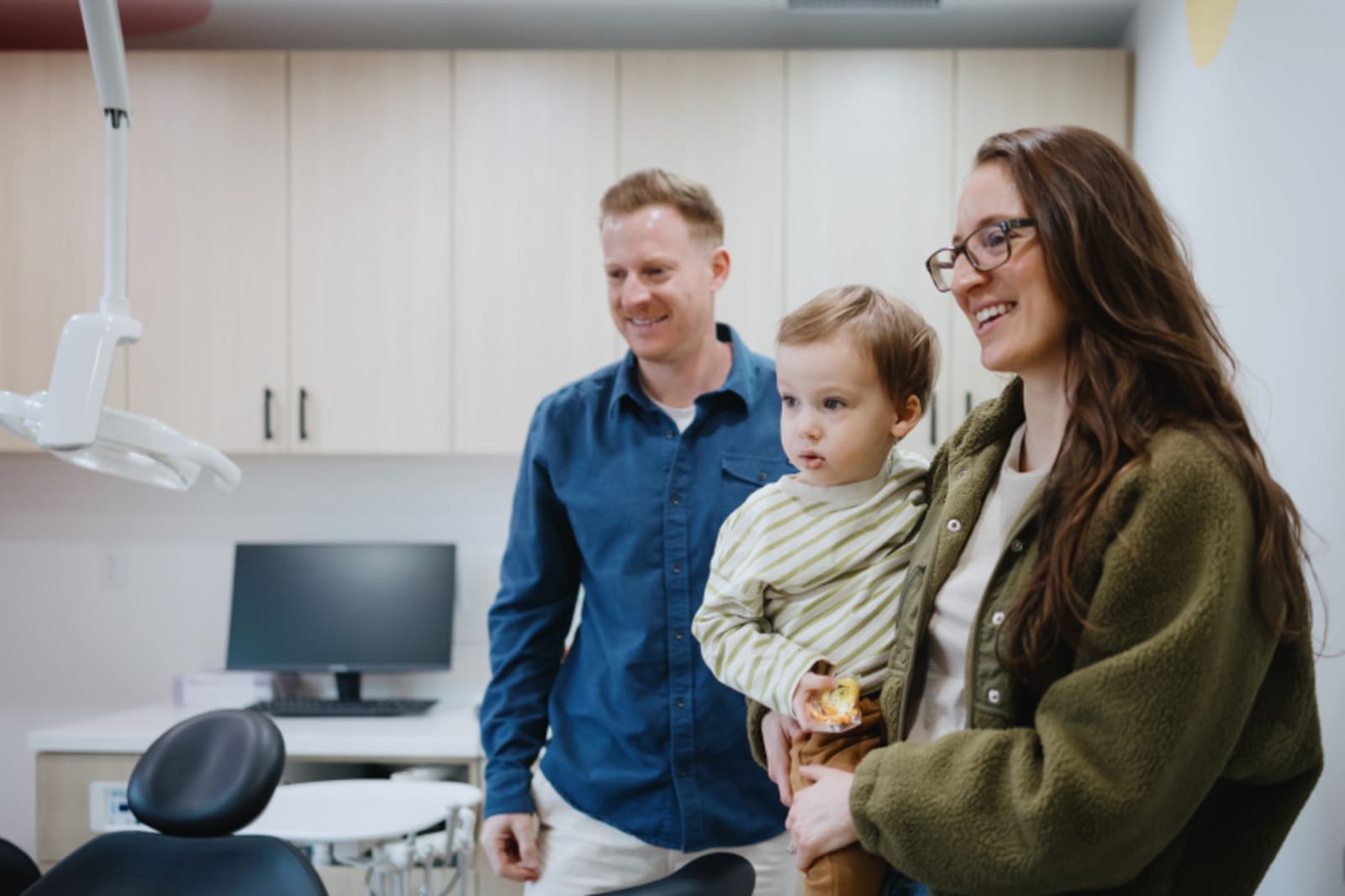 Dentist and dental team members with a young patient and parent in treatment area