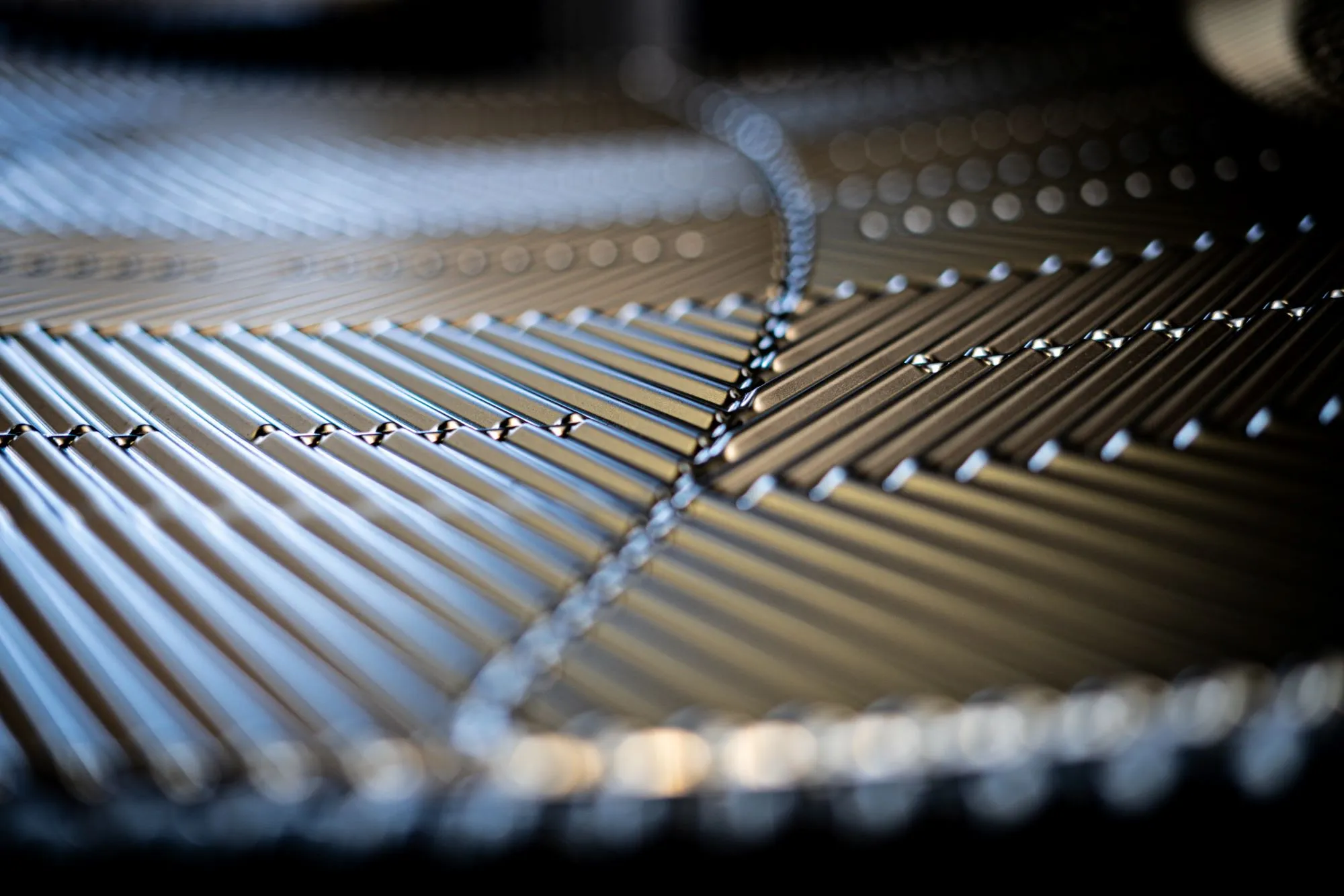 Nærbillede af glinsende metalstrenge arrangeret i et mønster med diagonal linje i fokus.