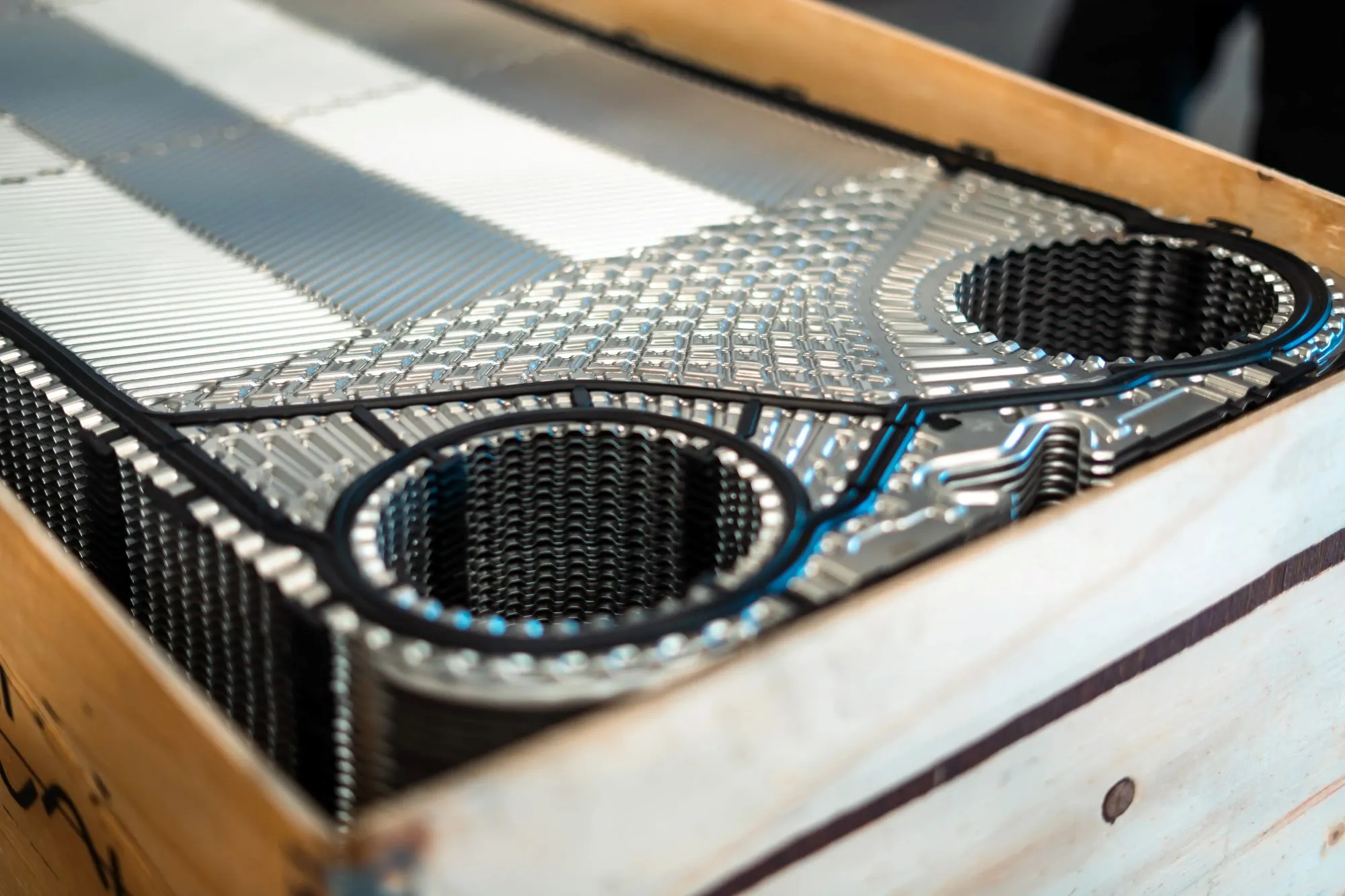 En stak metalplader med mønstrede overflader og runde udskæringer lagt i en træramme.