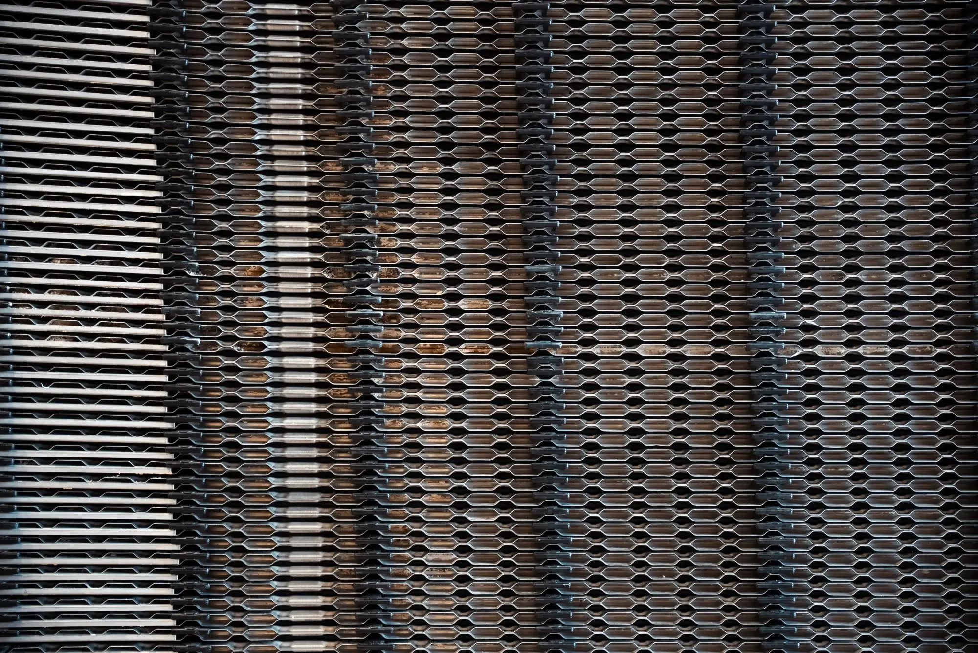 Nærbillede af overlappende metalplader med mønster af aflange huller.