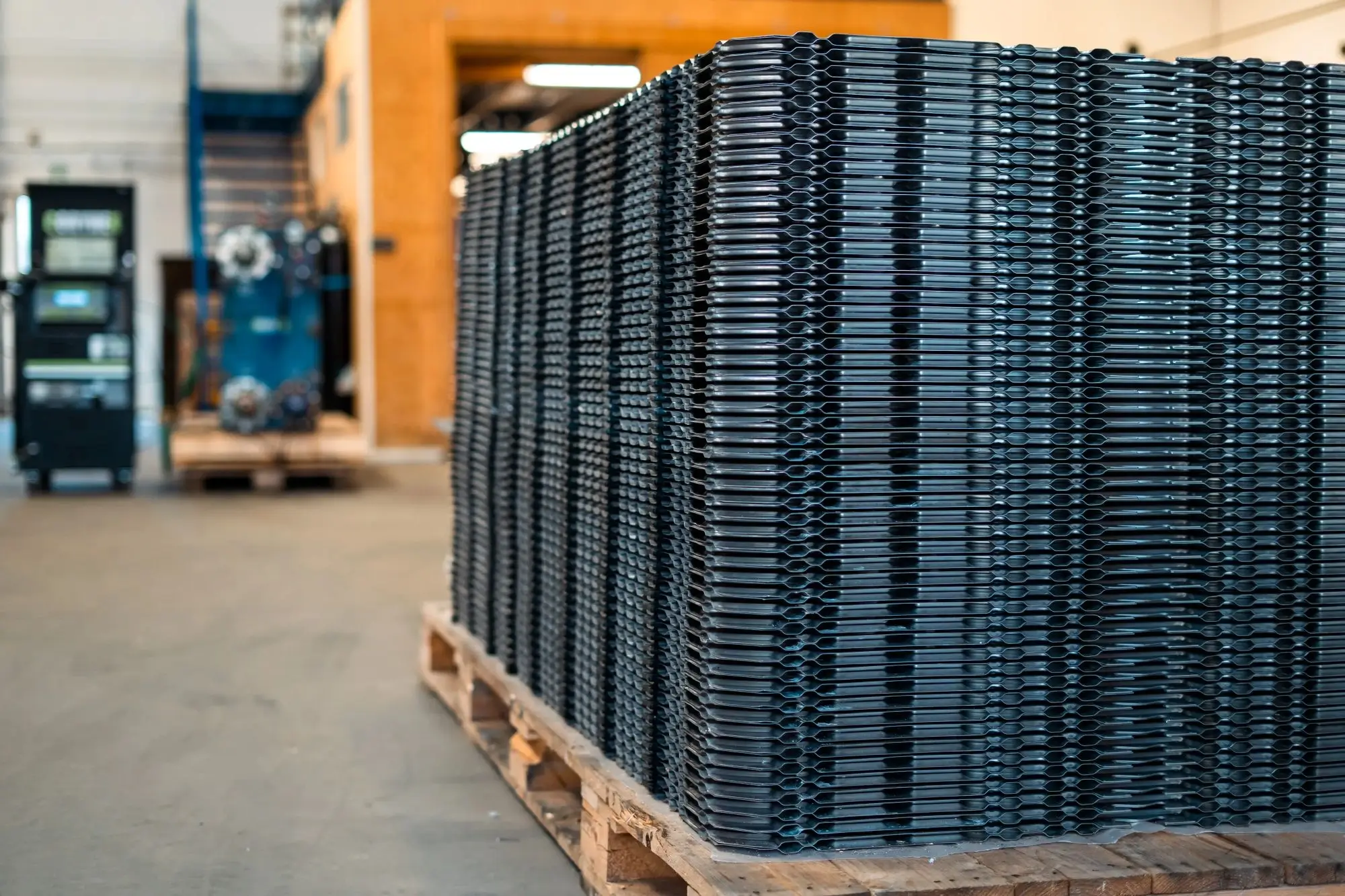 Stable af metalgitre stablet på en træpalle i en industriel lagerhal.