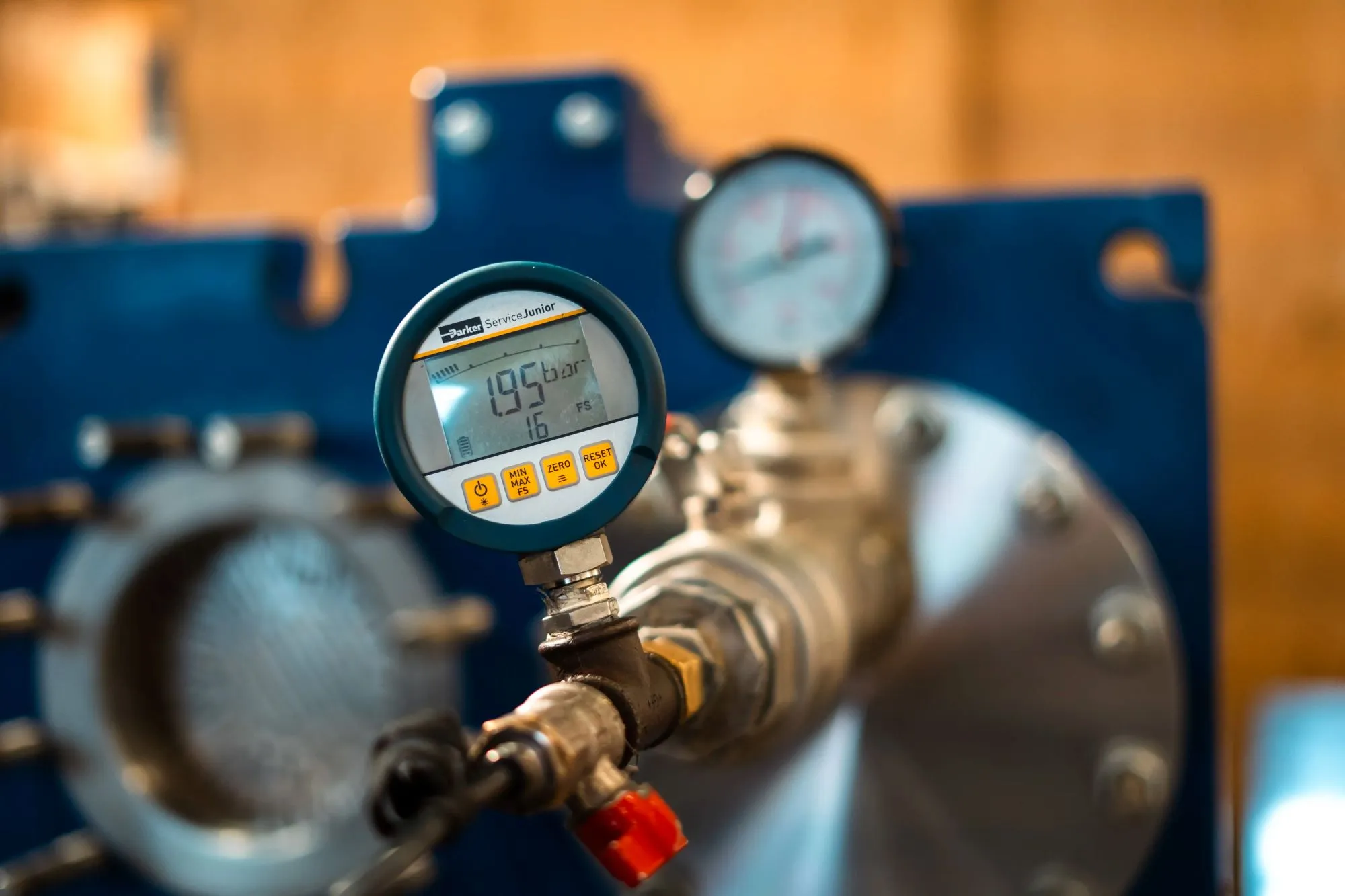 Digitalt trykmåler viser 1,95 bar på en metalventil i et industrimiljø.