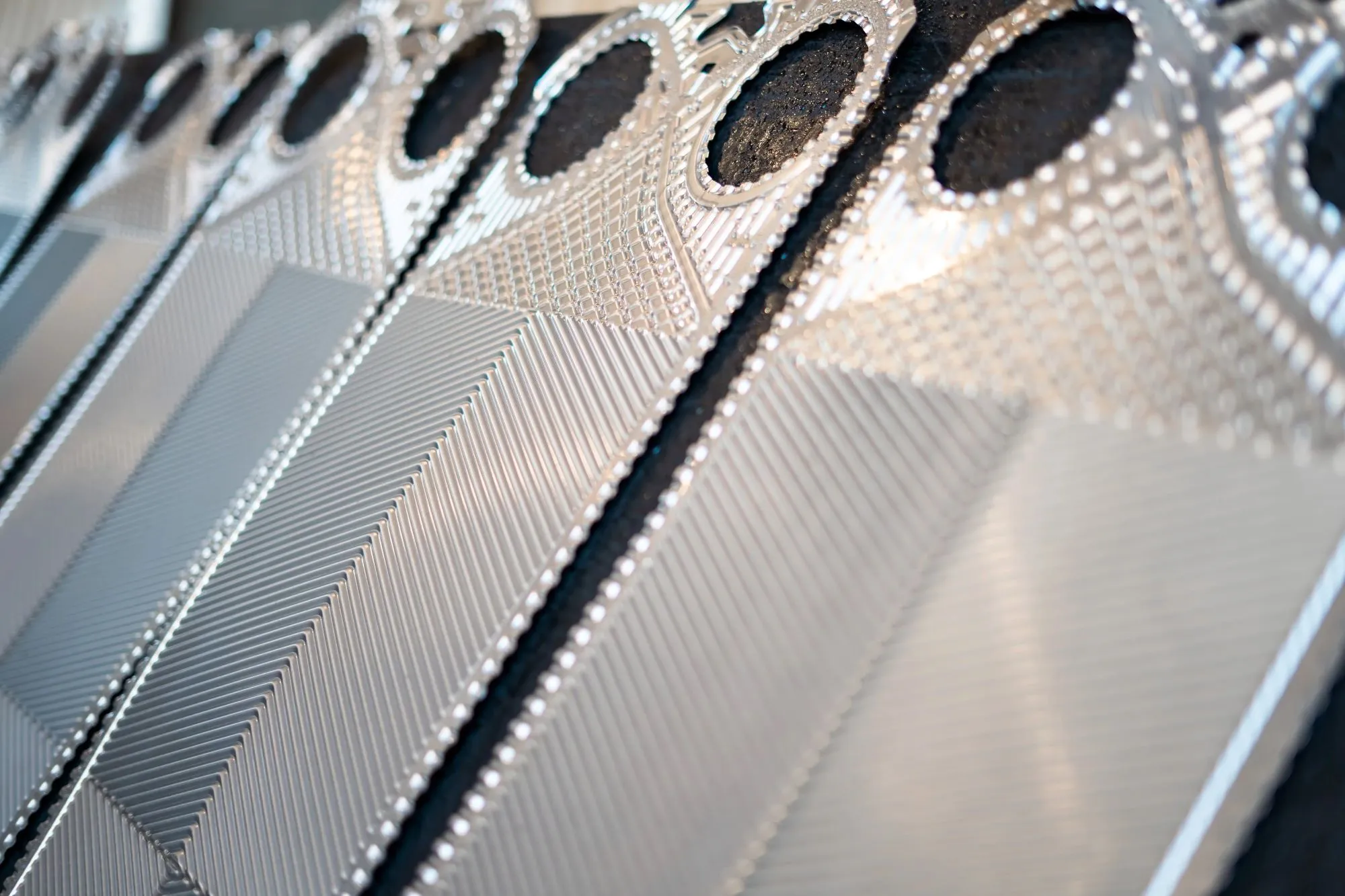 Nærbillede af metalplader med skarpe, præcise mønstre og riflet tekstur i sølvfarve.