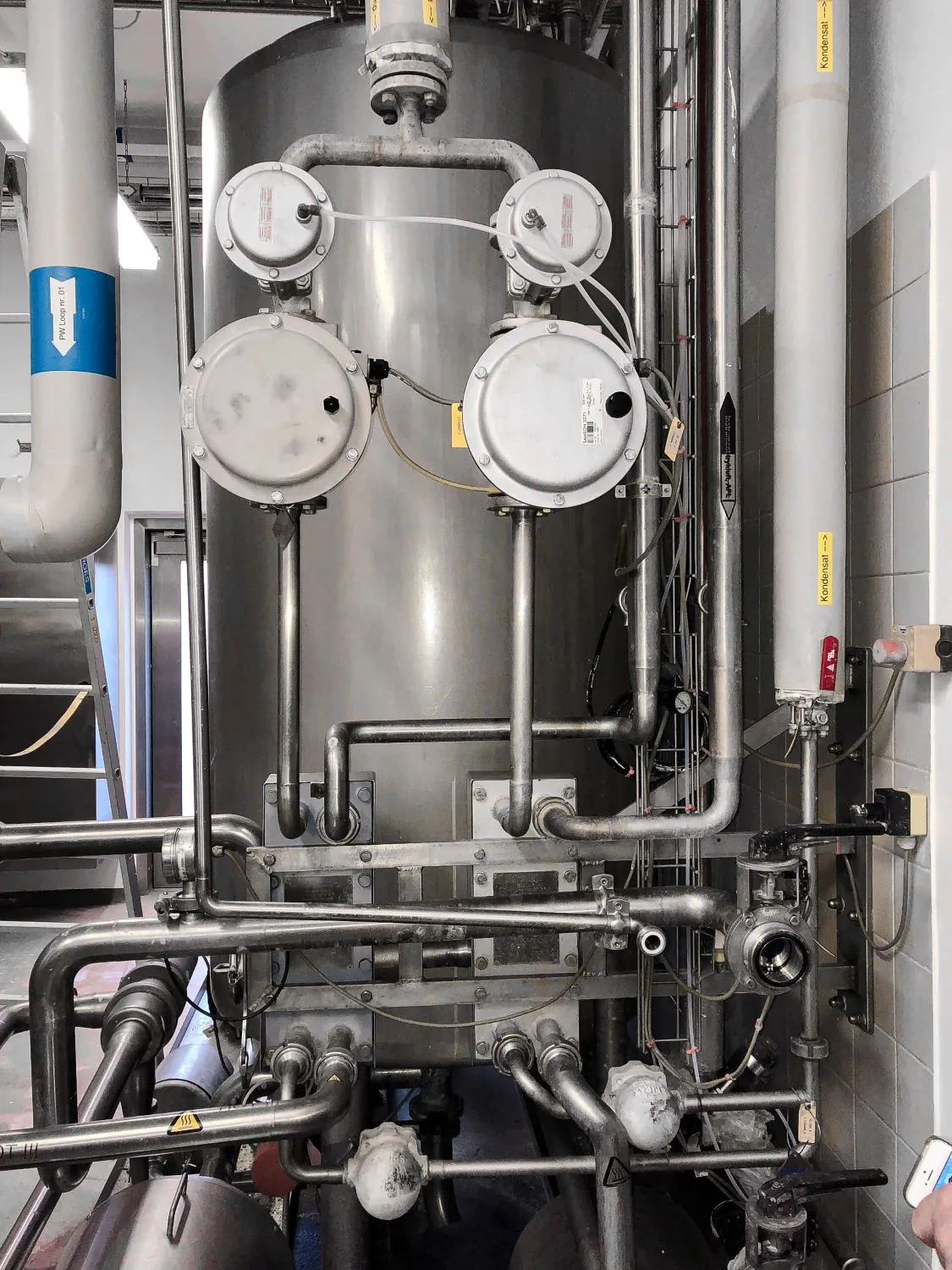 Industrielt anlæg med ståltanke, rør, ventiler og måleinstrumenter i en fabrik.