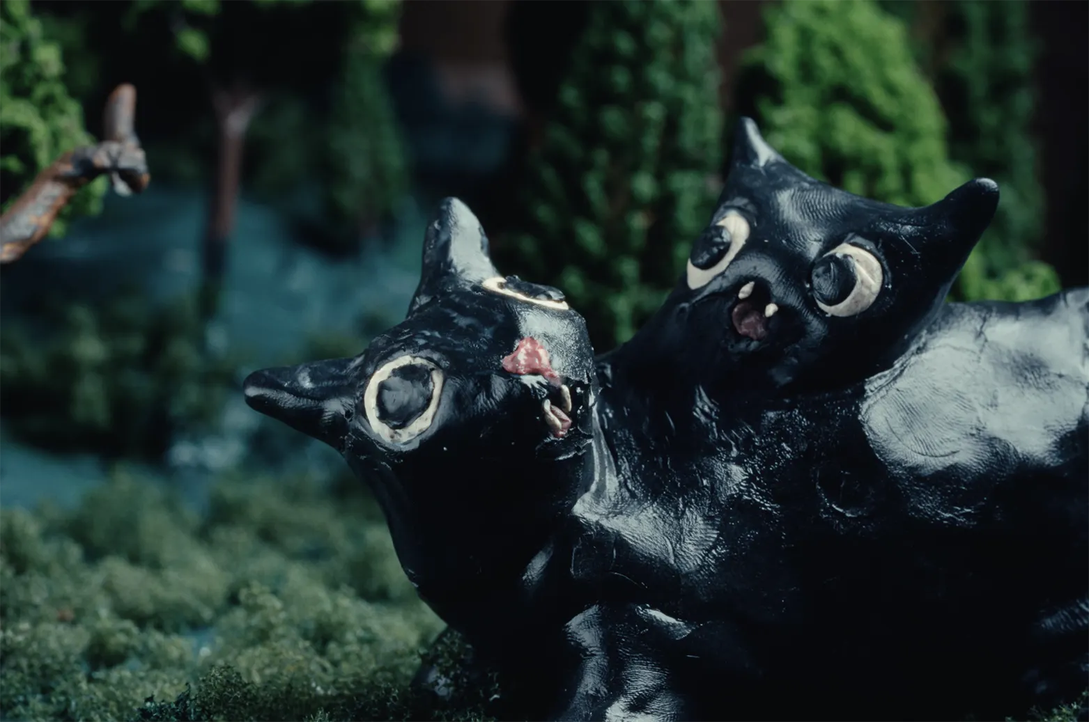 Stop-motion animation scene featuring handcrafted cat characters in a surreal forest environment.