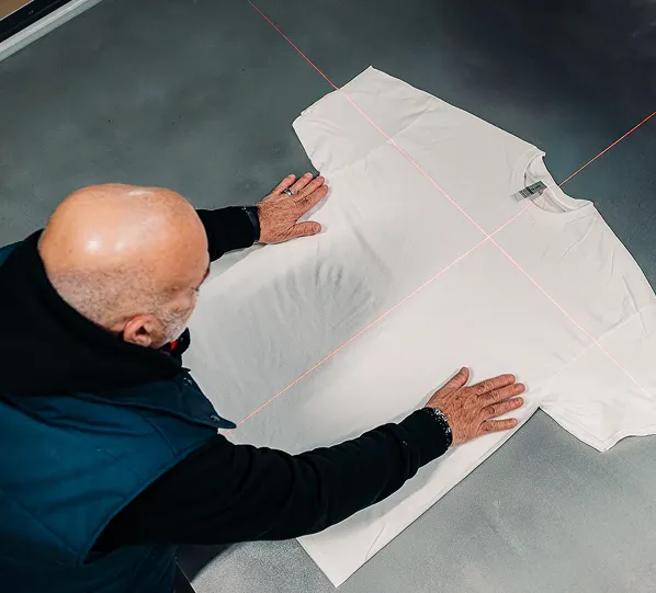 Collaborateur en train de positionner un t-shirt blanc prêt à être découpé en empiècements