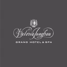 Victoria Jungfrau Grand Hotel & Spa logo with elegant script and emblem on dark background.