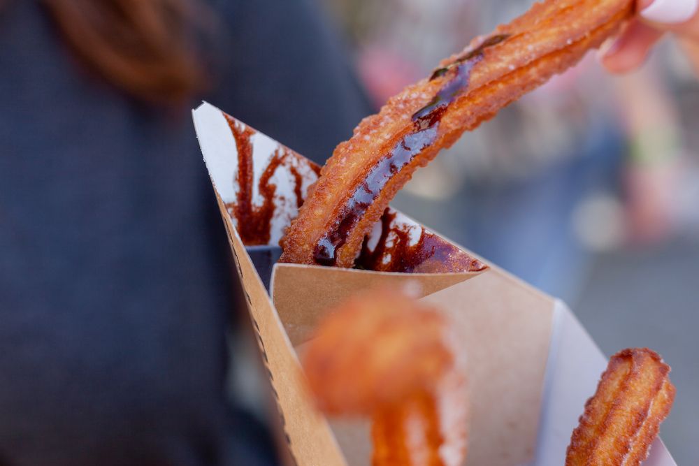 churros being dipped in chocolate