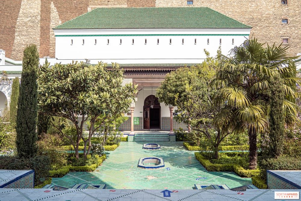 Green tiled fountain with a garden and white building with a green rooftop
