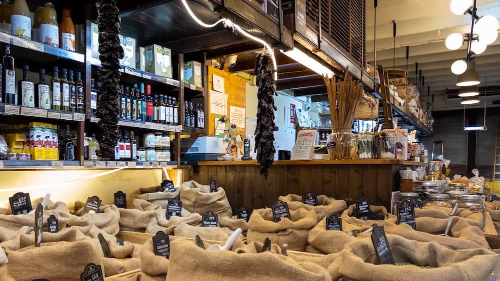 Grains in open sacks and olive oil on the shelves in a shop