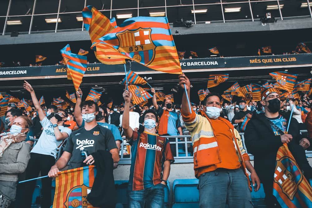 fans of fc barcelona cheer and raise flags