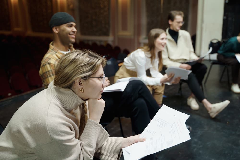 A group of people sit in a row with papers on their laps