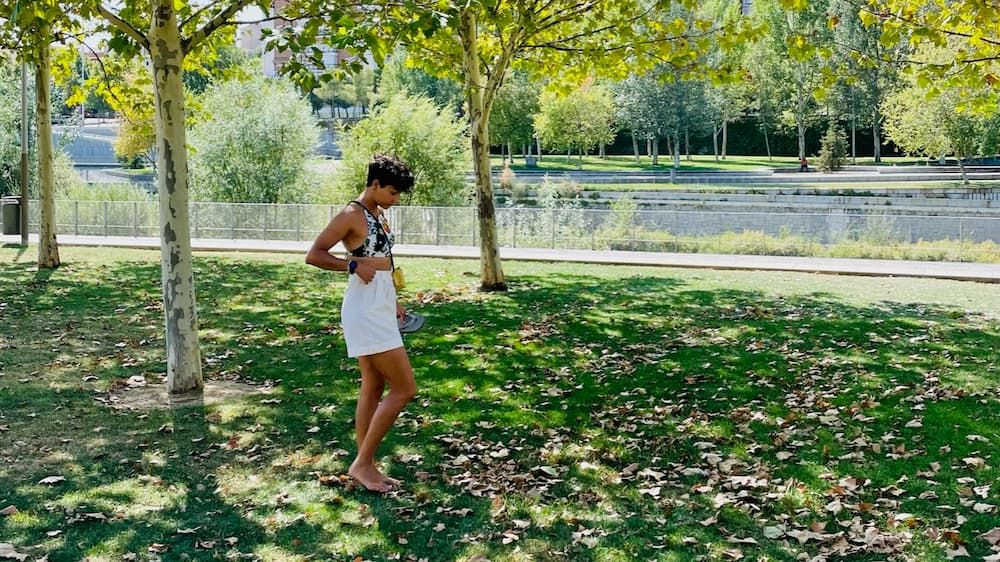 A girl walking through a shaded grassy area in a park