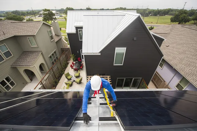Primo piano di un tecnico al lavoro su un impianto fotovoltaico su un tetto di un'abitazione