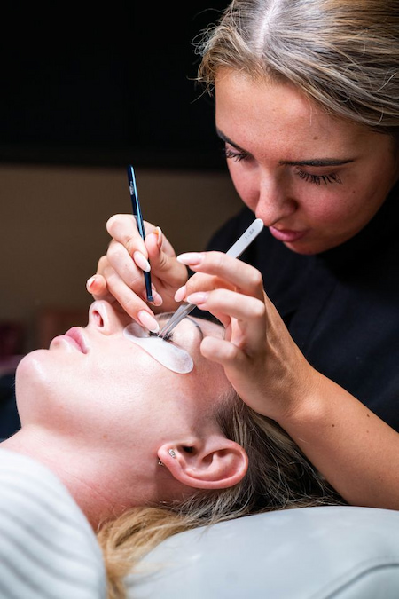 Lash artist isolating a natural lash with tweezers during application