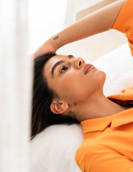Woman relaxing on a bed with her arm over her head