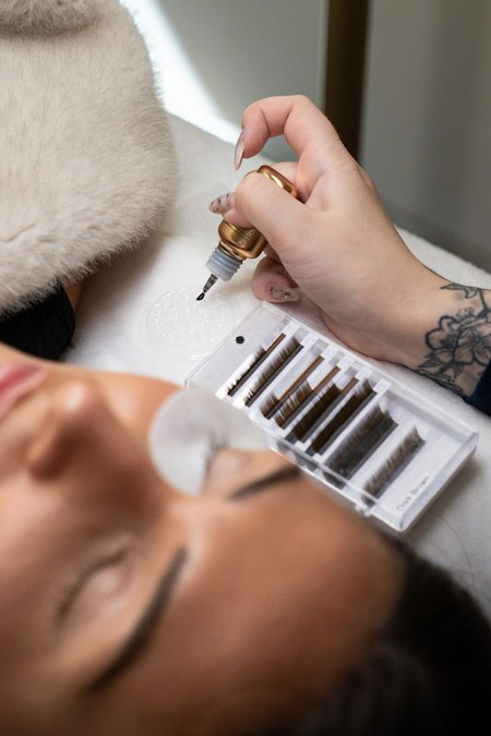 Lash tray and adhesive beside a client having lash extensions applied