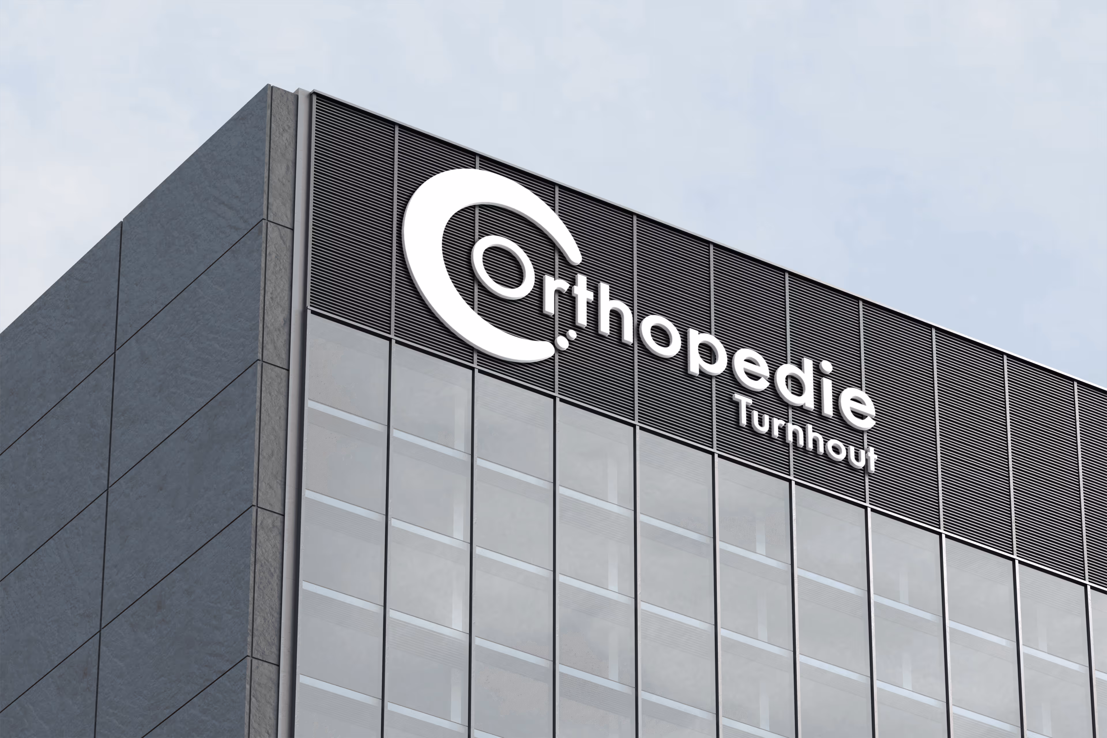 Modern gebouwhoek met glazen gevel en geel strak logo Orthopedie Turnhout bovenaan.