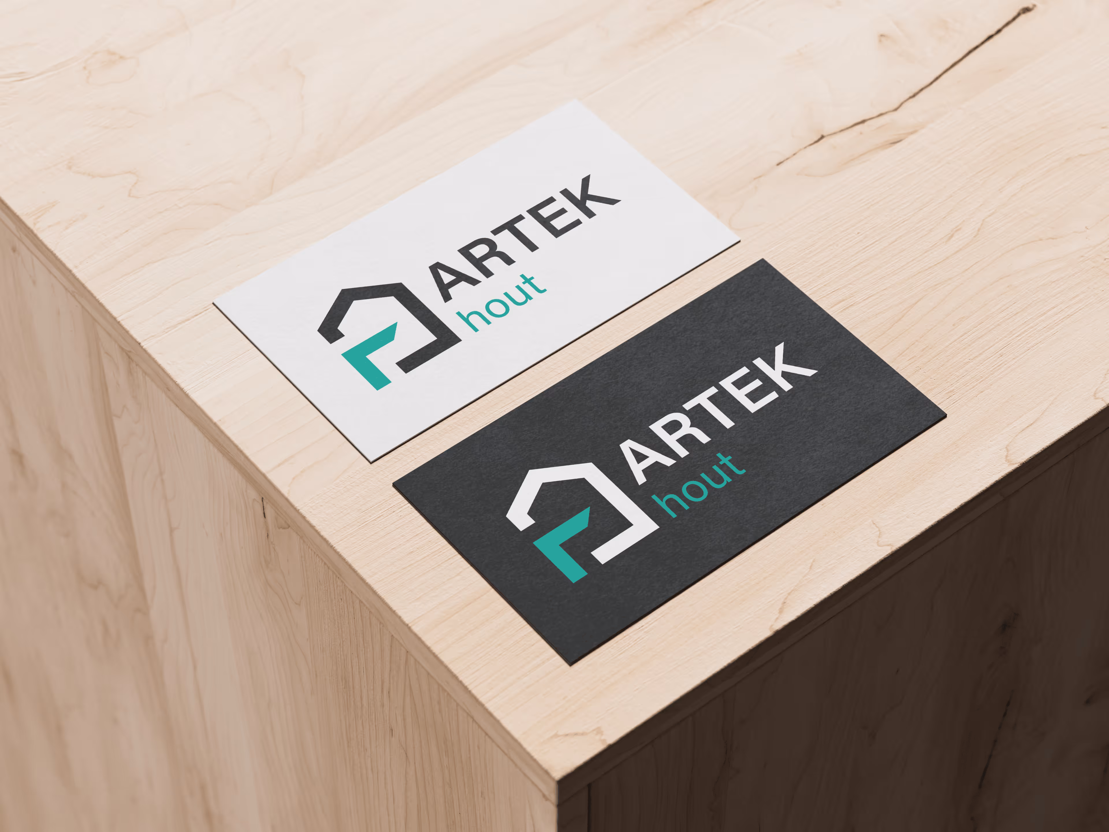 Twee visitekaartjes met logo en tekst 'ARTEK hout' op een houten tafel, één kaartje wit, de ander zwart.