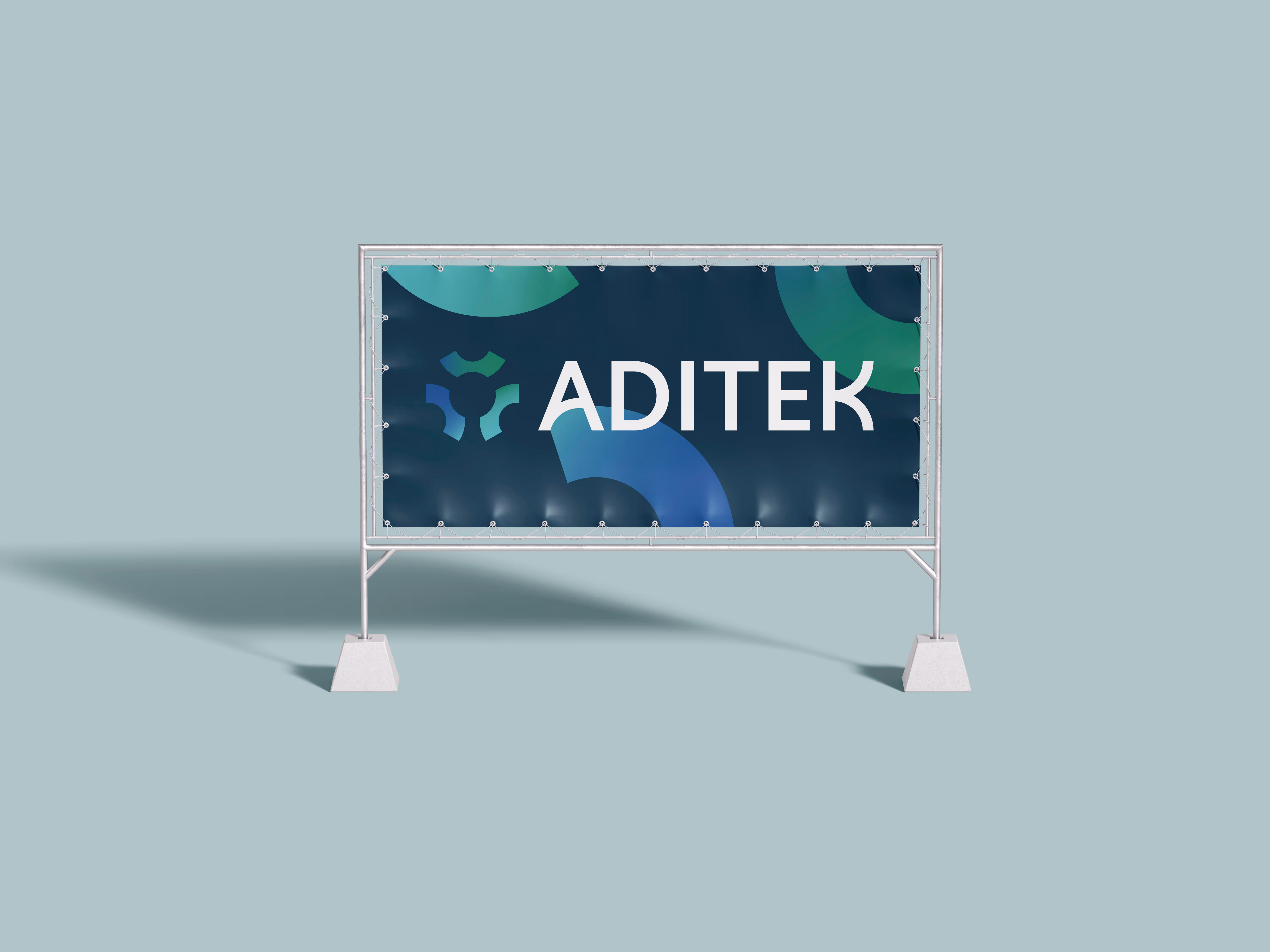 Reclamebanner met het logo en de tekst 'ADITEK' op een blauwe en groene achtergrond, geplaatst in een metalen frame met betonnen bases.