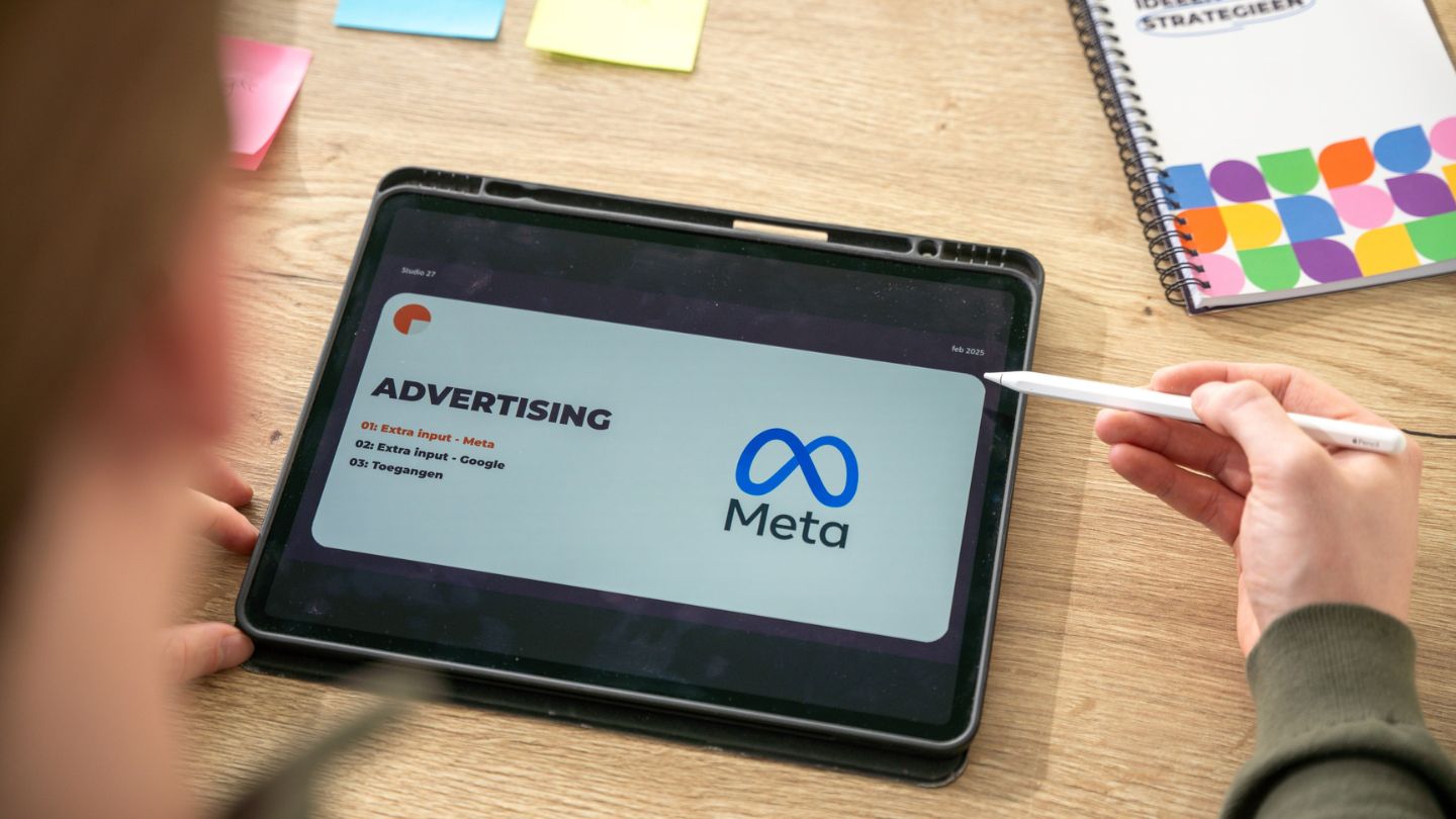 Een iPad op een houten tafel met op scherm: Advertising met Meta.