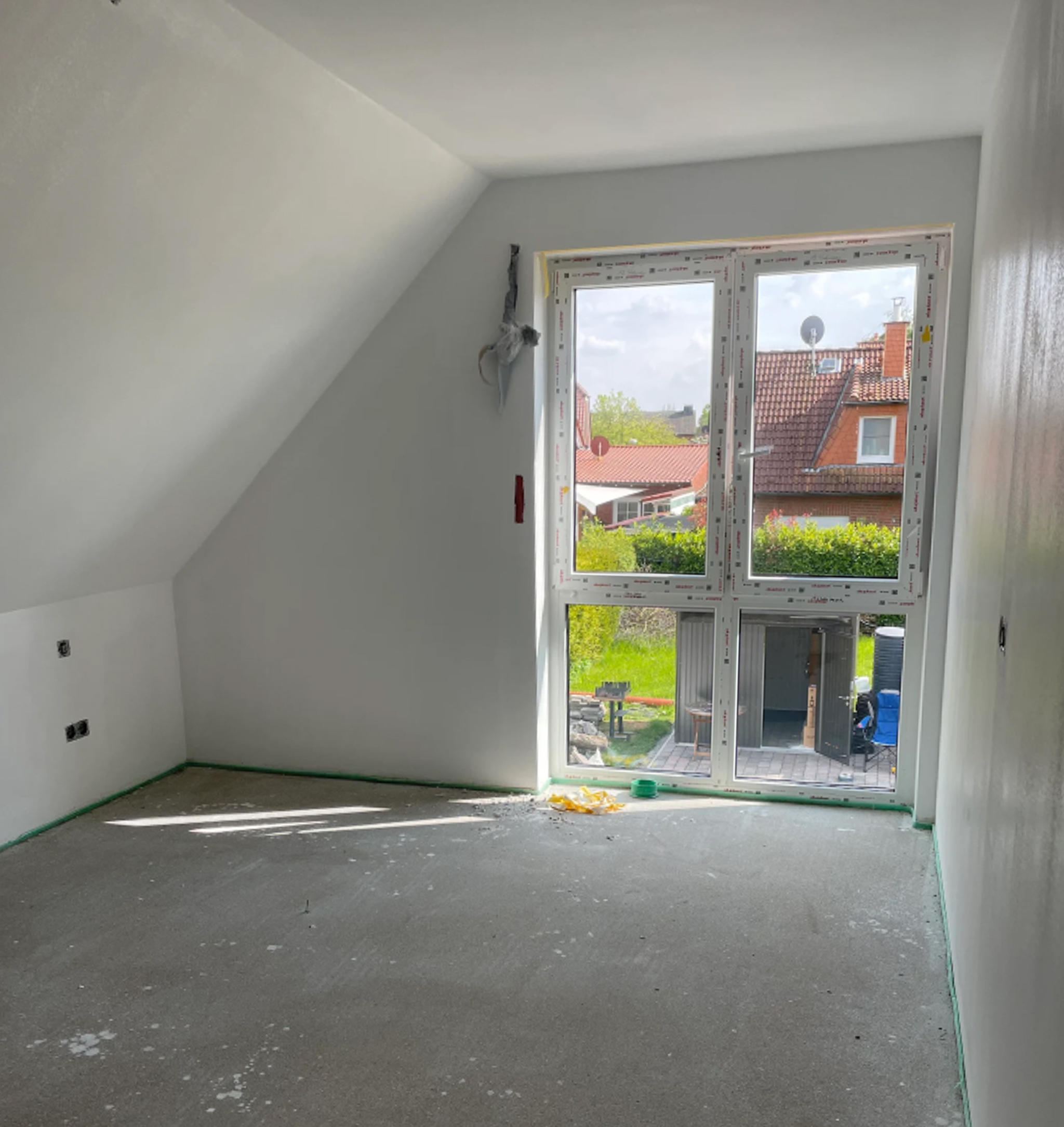 Malerbetrieb Münster: Frisch gestrichener Dachraum mit großem Fenster und Gartensicht