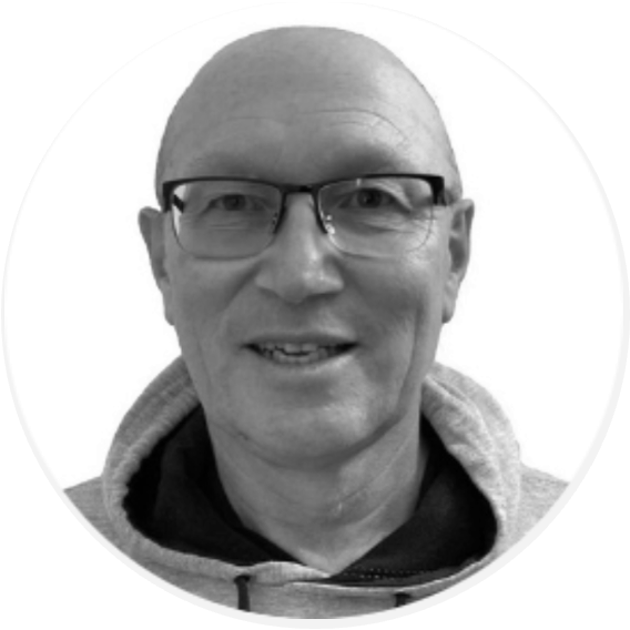 Black and white portrait of a smiling bald man wearing glasses and a hoodie.