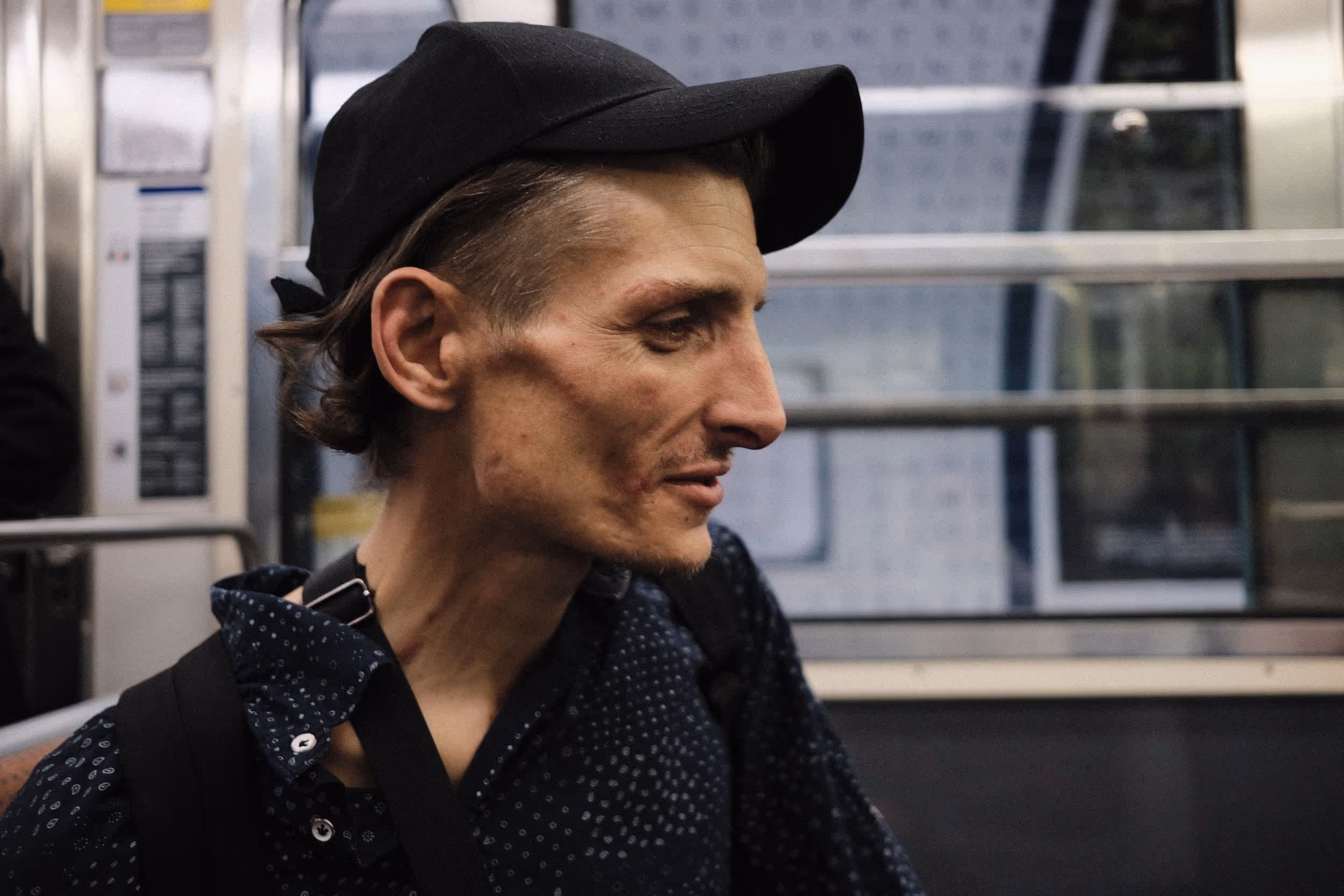 Portrait d’un homme en casquette dans une rame de métro, regard tourné vers la gauche.