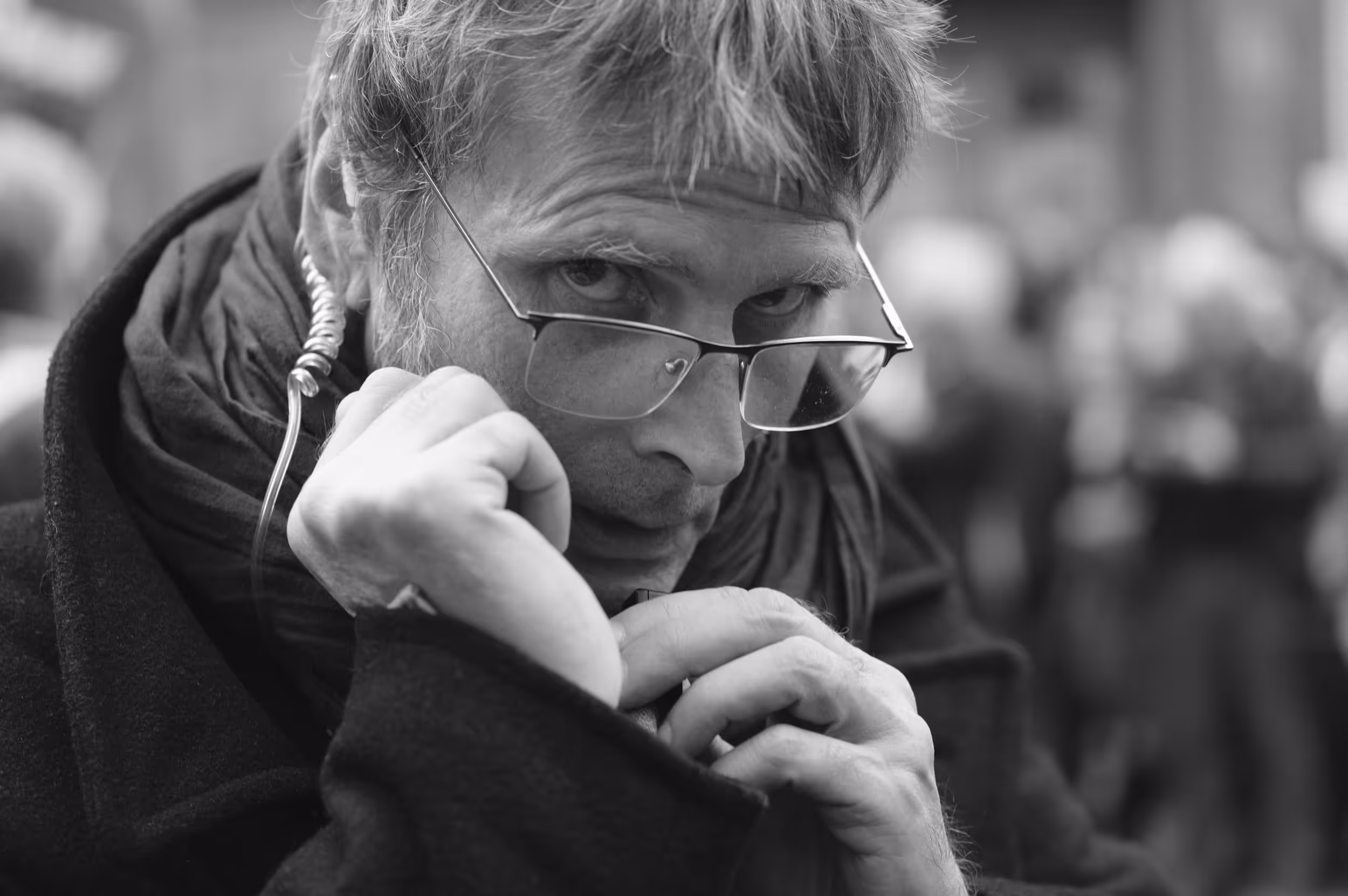 Portrait rapproché d’un homme regardant fixement l’objectif, écouteur enroulé autour de l’oreille.