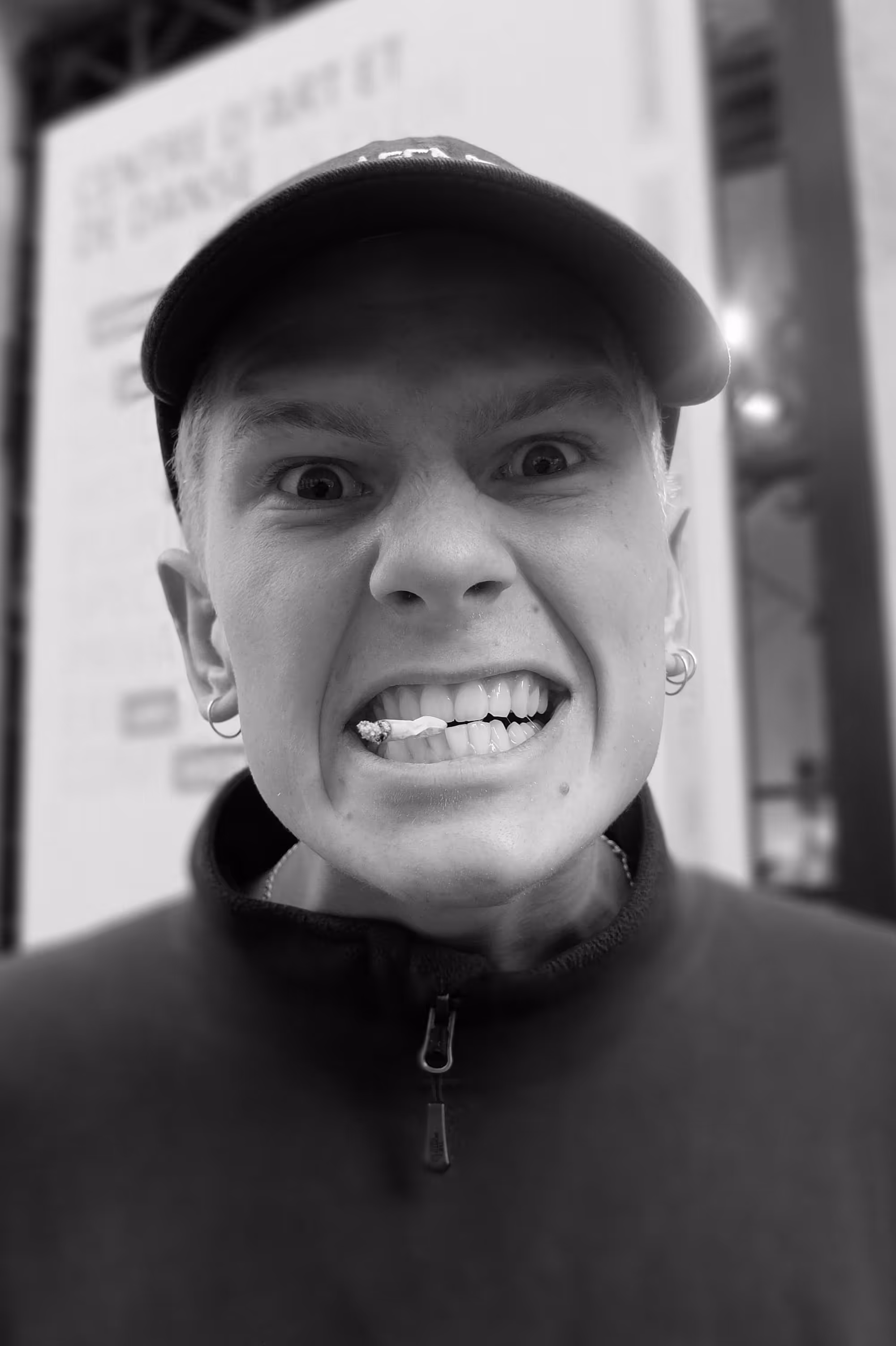 Jeune homme faisant une grimace avec un chewing-gum coincée entre ses dents, photographié en gros plan.