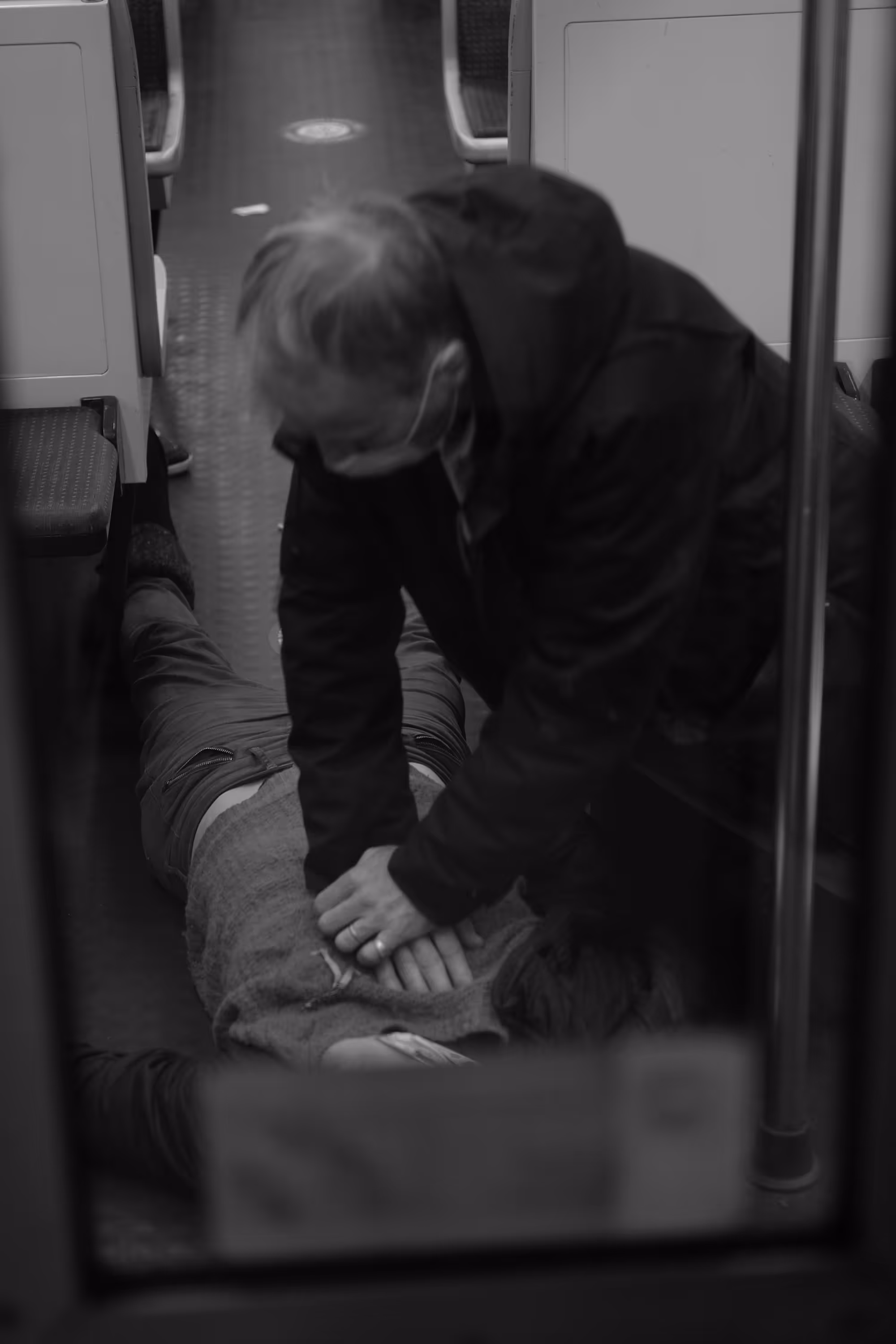 Un homme effectue un massage cardiaque sur une personne allongée dans une rame de métro vide.