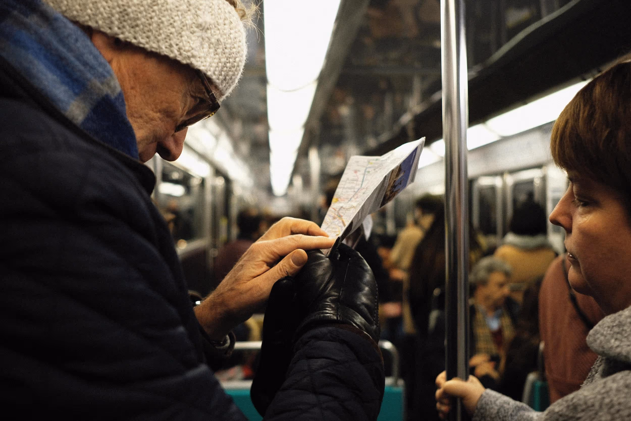 Un homme et une femme consultent une carte du métro dans une rame, entourés de passagers.