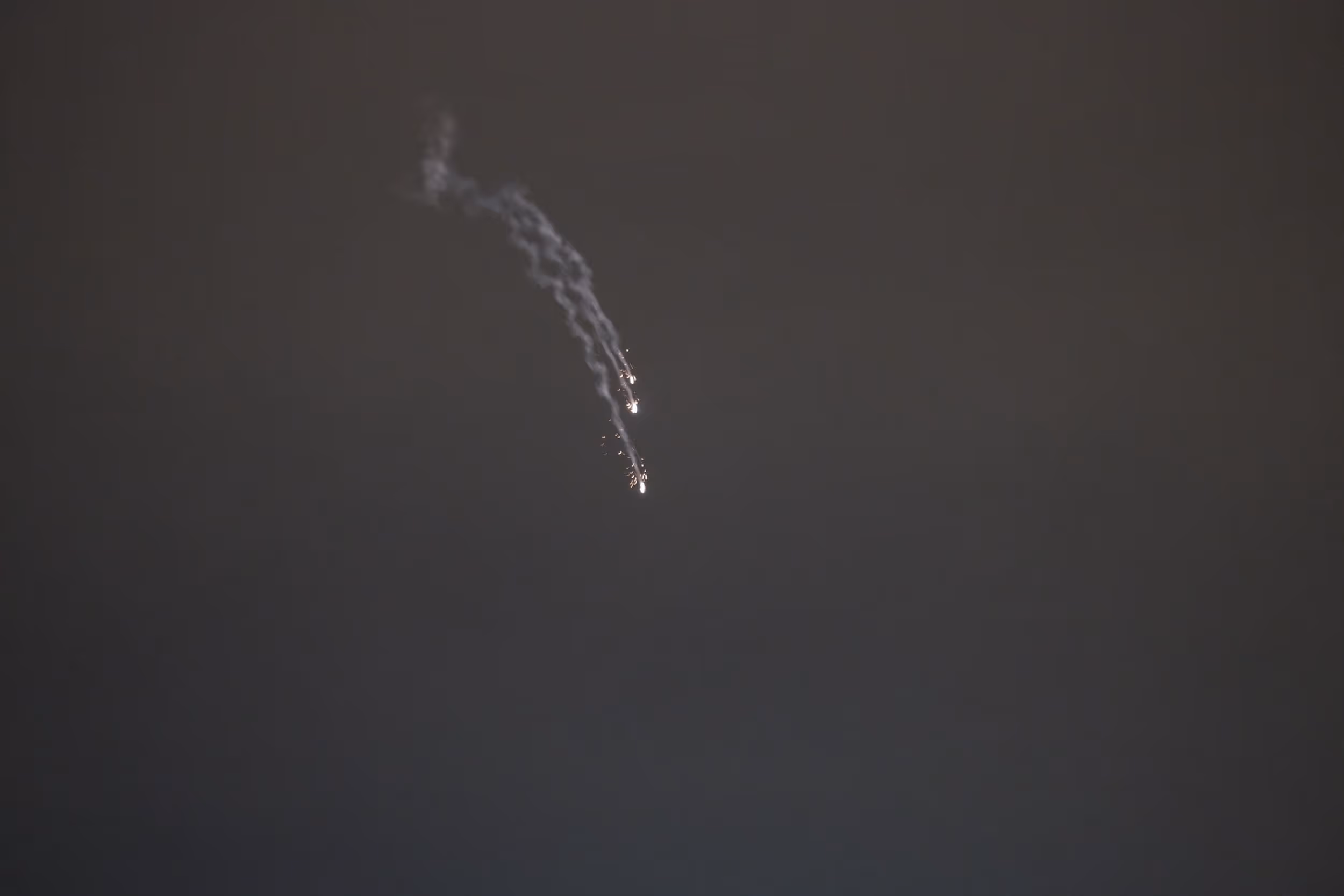 Traînées lumineuses dans le ciel nocturne, laissant présumer un tir de projectile ou de feu d’artifice.