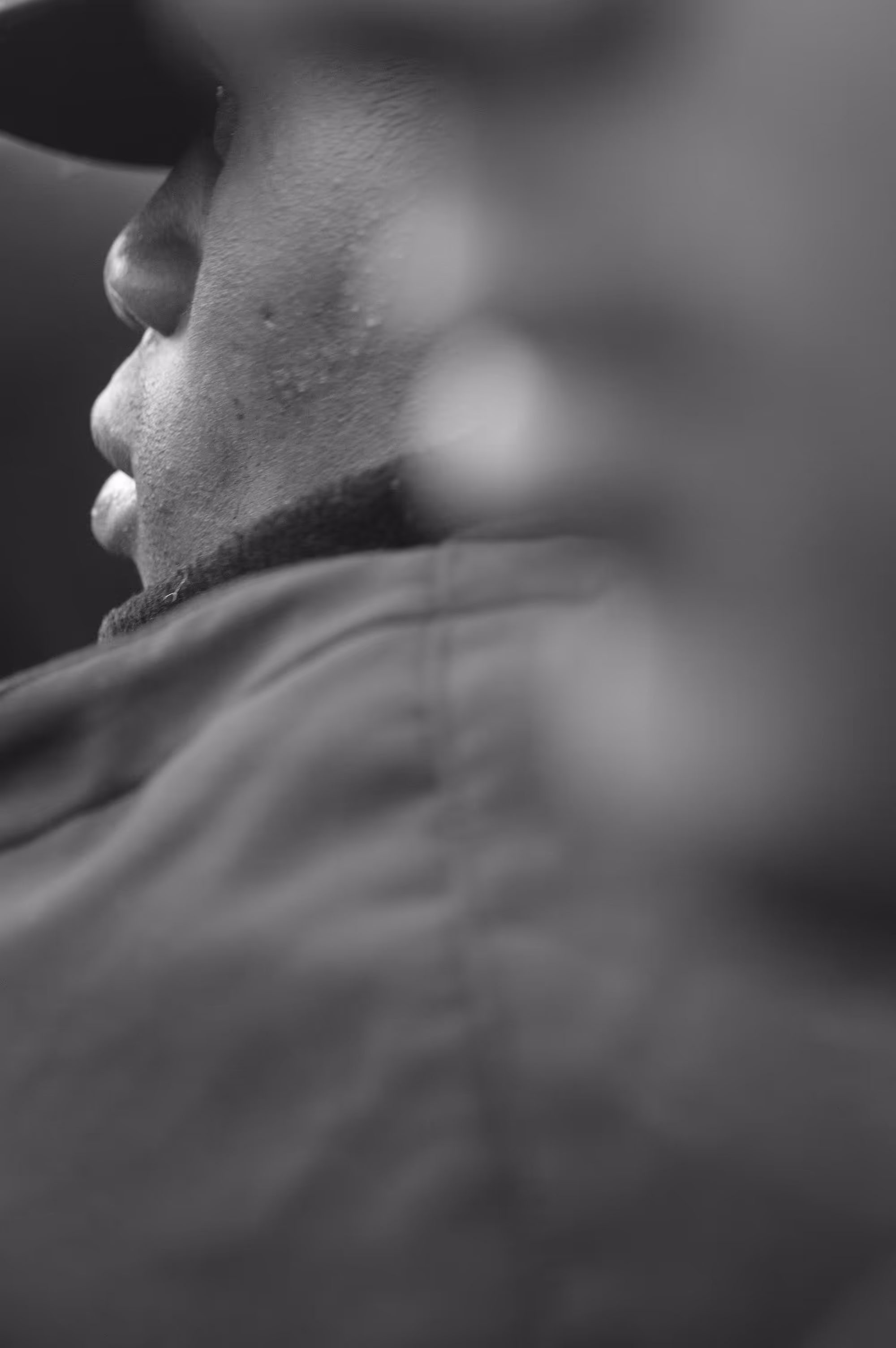 Portrait flou et serré d’un visage de profil, joues visibles, ambiance introspective.