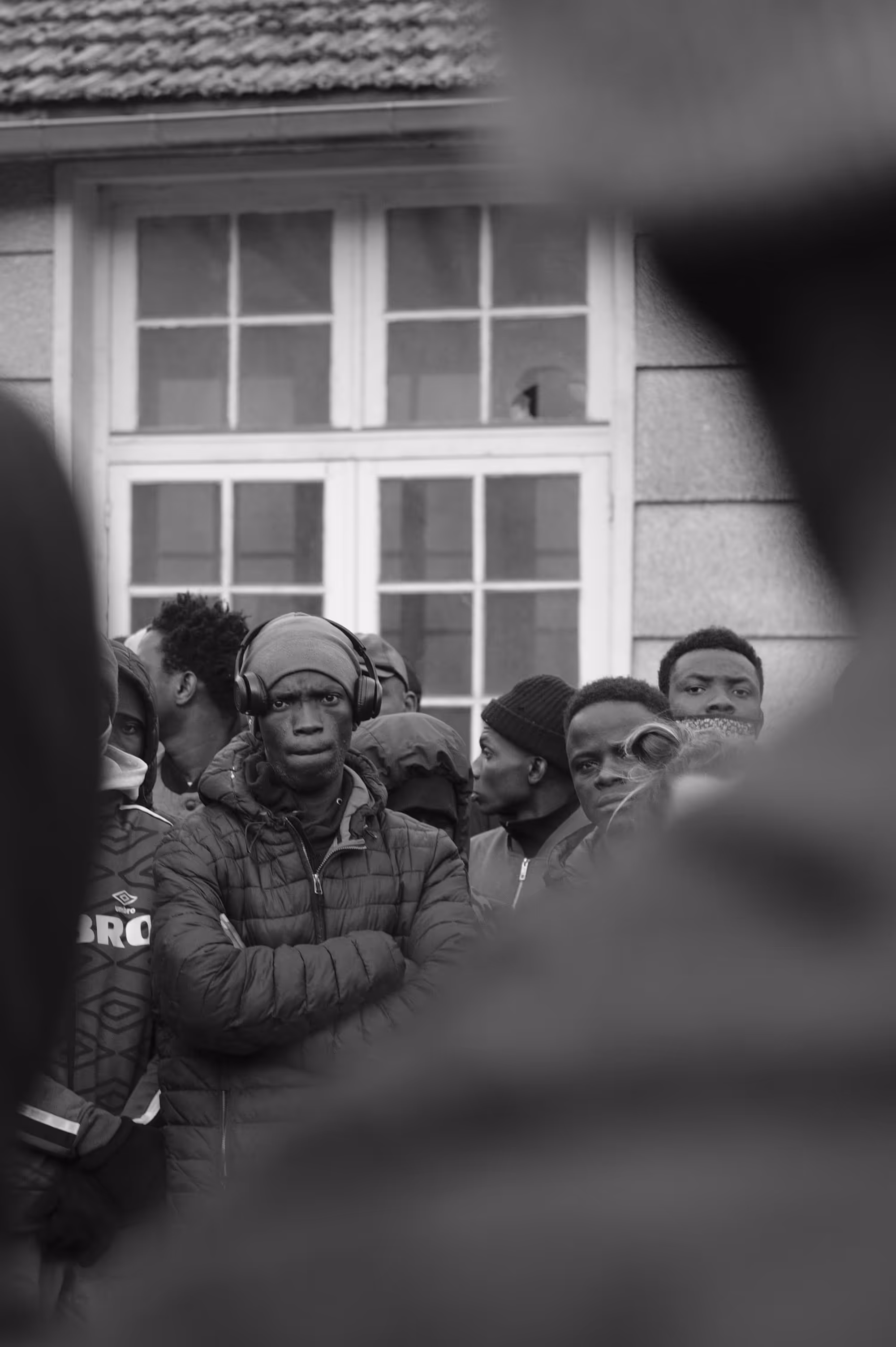 Jeunes hommes dans une cour, visages concentrés, certains portent des casques audio.