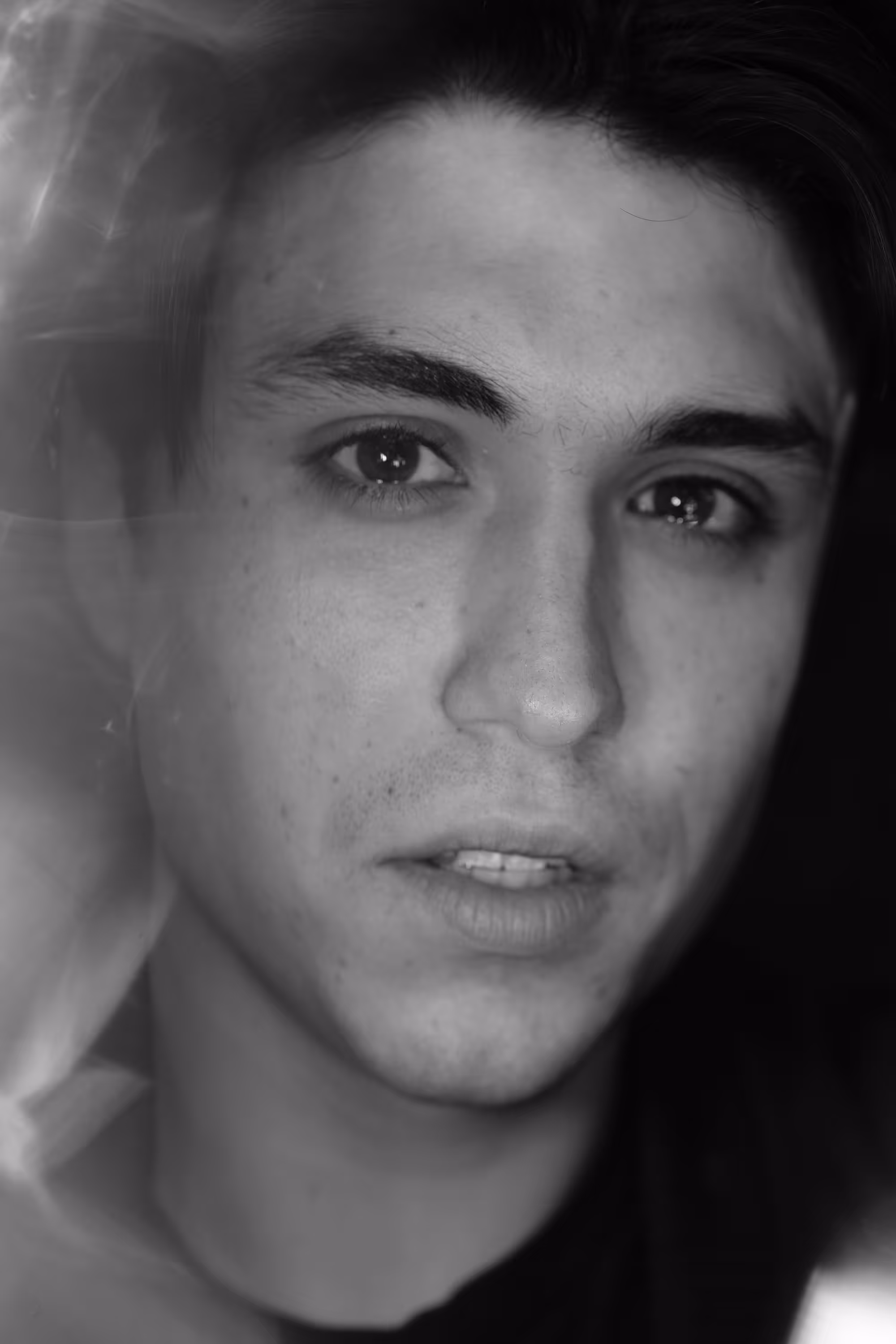 Portrait rapproché d’un homme au regard intense, légèrement flouté sur les bords pour créer une sensation de mouvement.