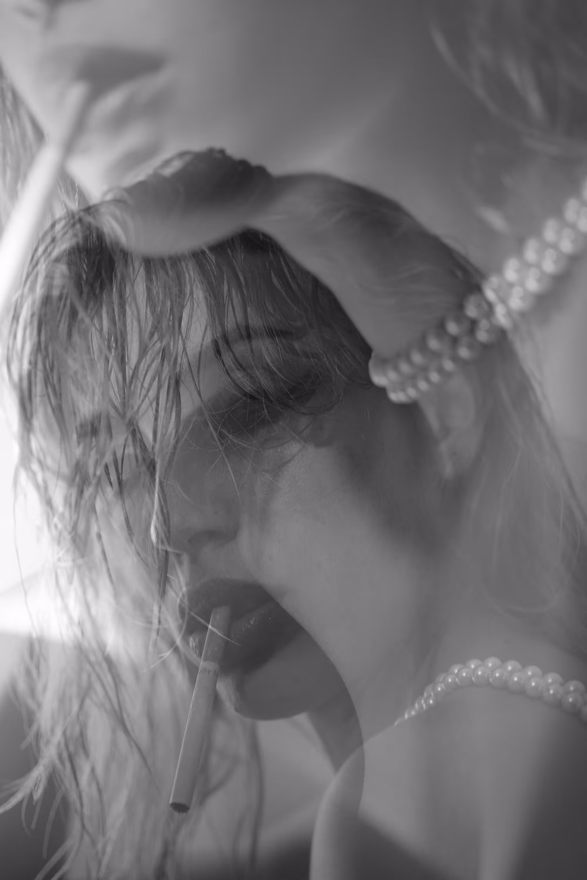 Double exposition d’un visage féminin avec des perles au cou et une cigarette entre les lèvres.