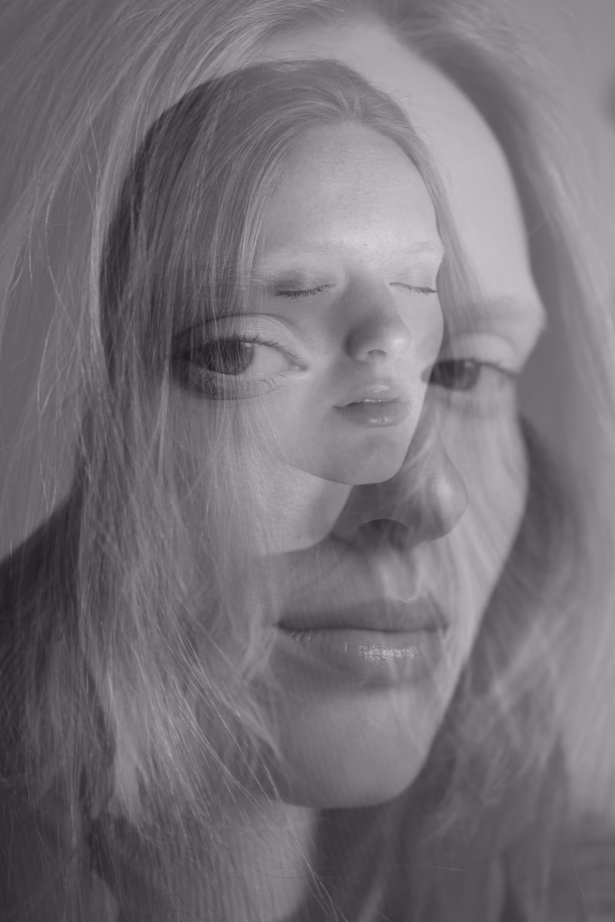 Portrait en double exposition d'une femme aux longs cheveux clairs, avec une superposition de son propre visage aux yeux fermés et ouverts, créant un effet de réflexion intérieure.