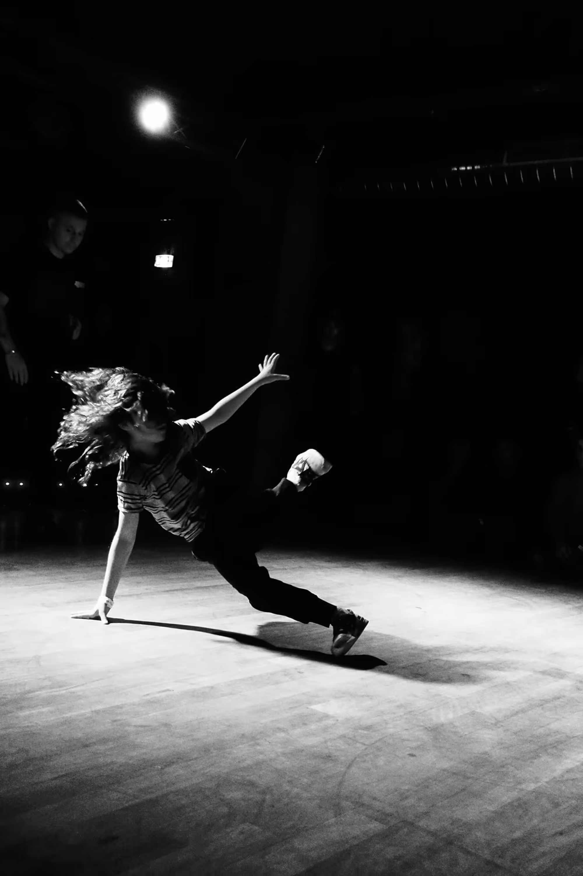 Danseuse aux longs cheveux en mouvement, réalisant une rotation dynamique au sol.