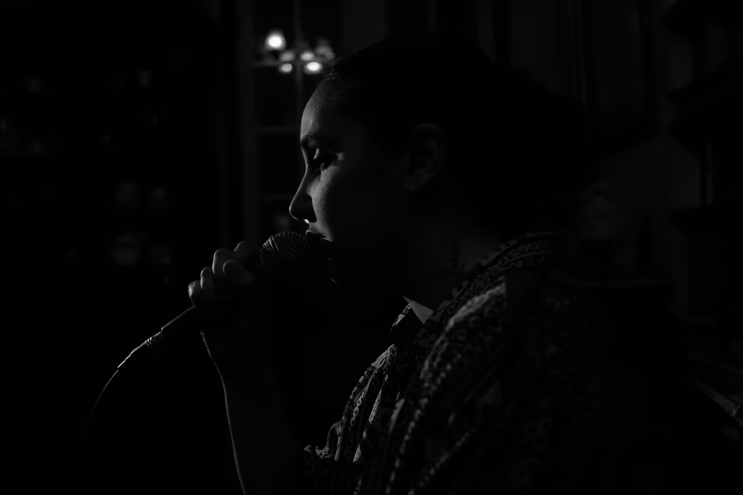 Portrait de profil d'une chanteuse dans une ambiance feutrée, micro près des lèvres.