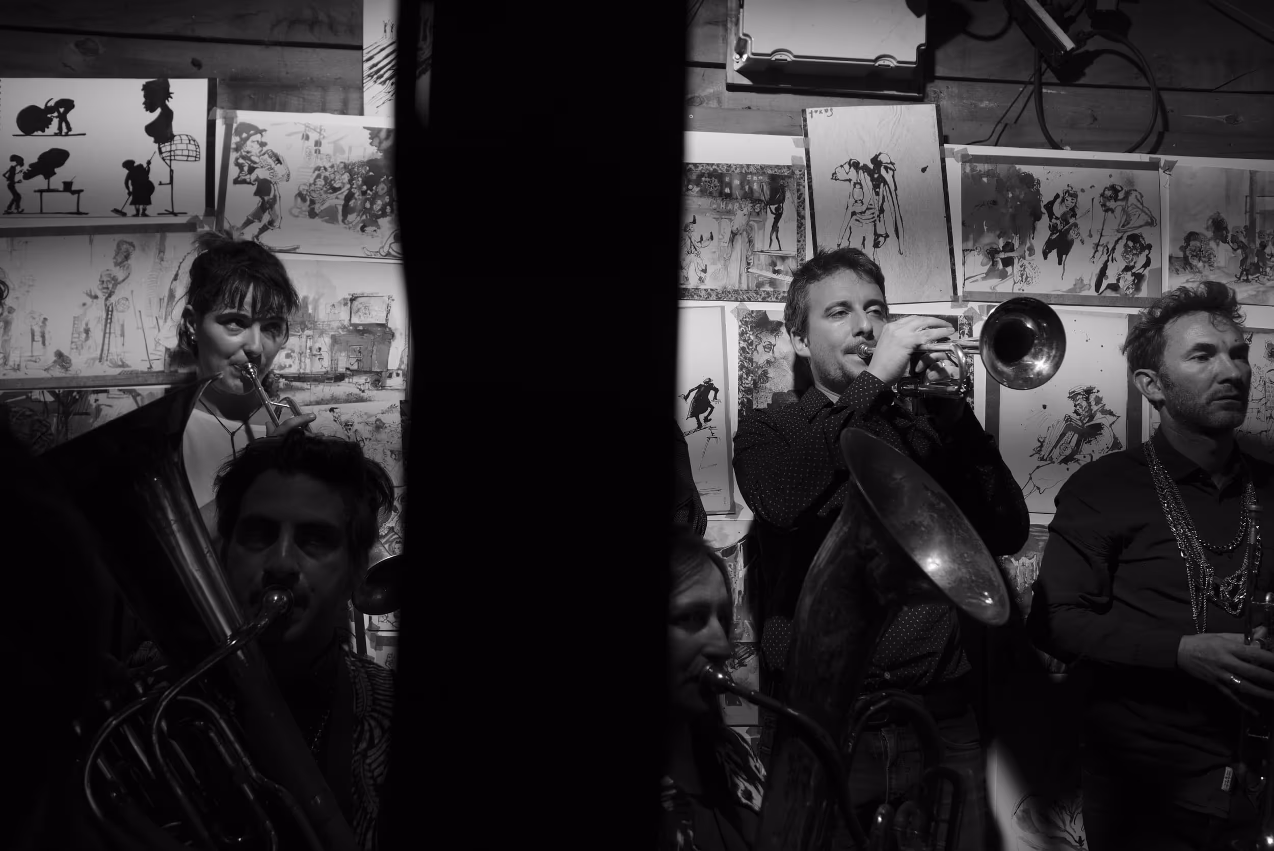 Musiciens de fanfare jouant dans un intérieur décoré de dessins, ambiance chaleureuse.