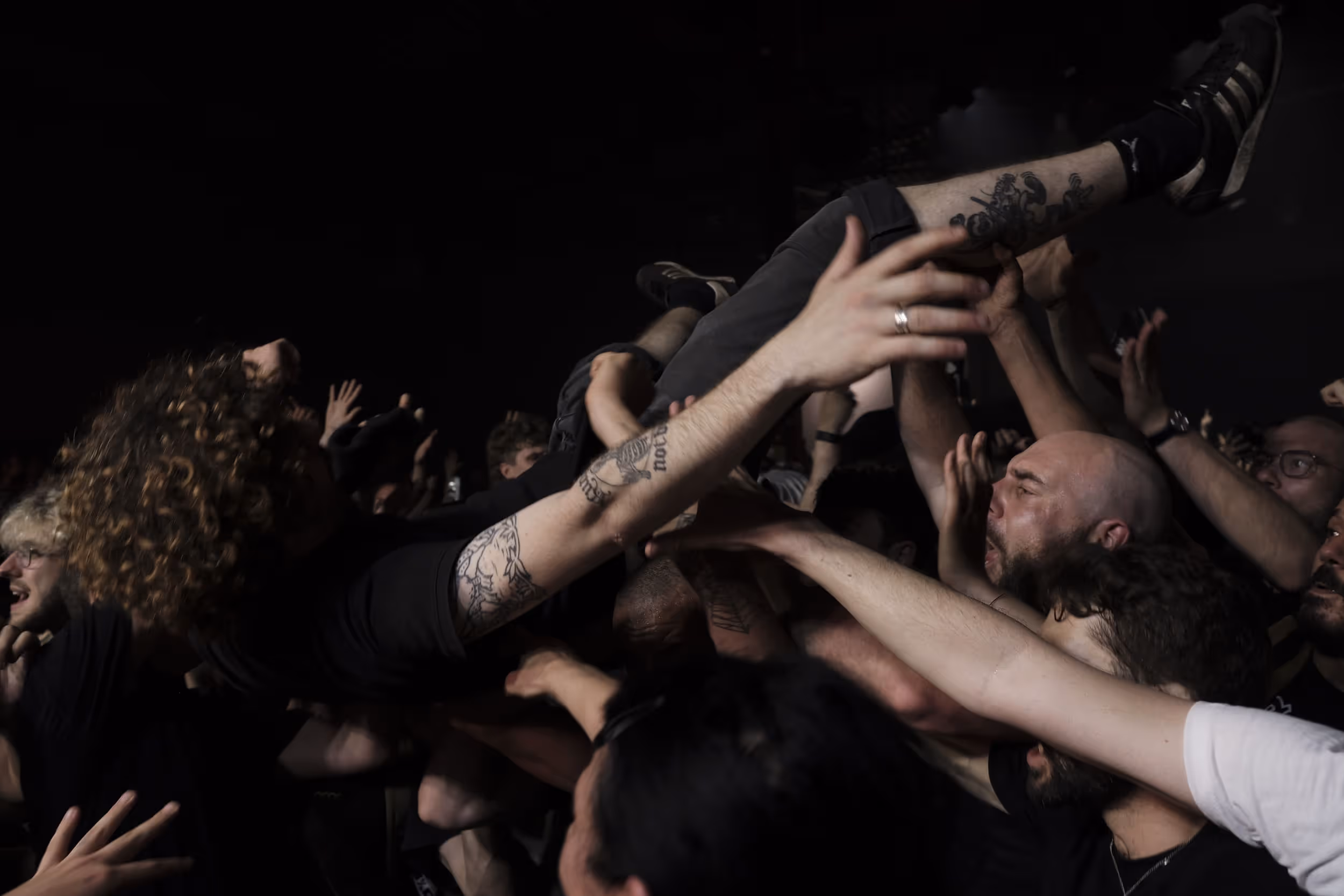 Foule portant un homme lors d’un concert de rock, ambiance survoltée.