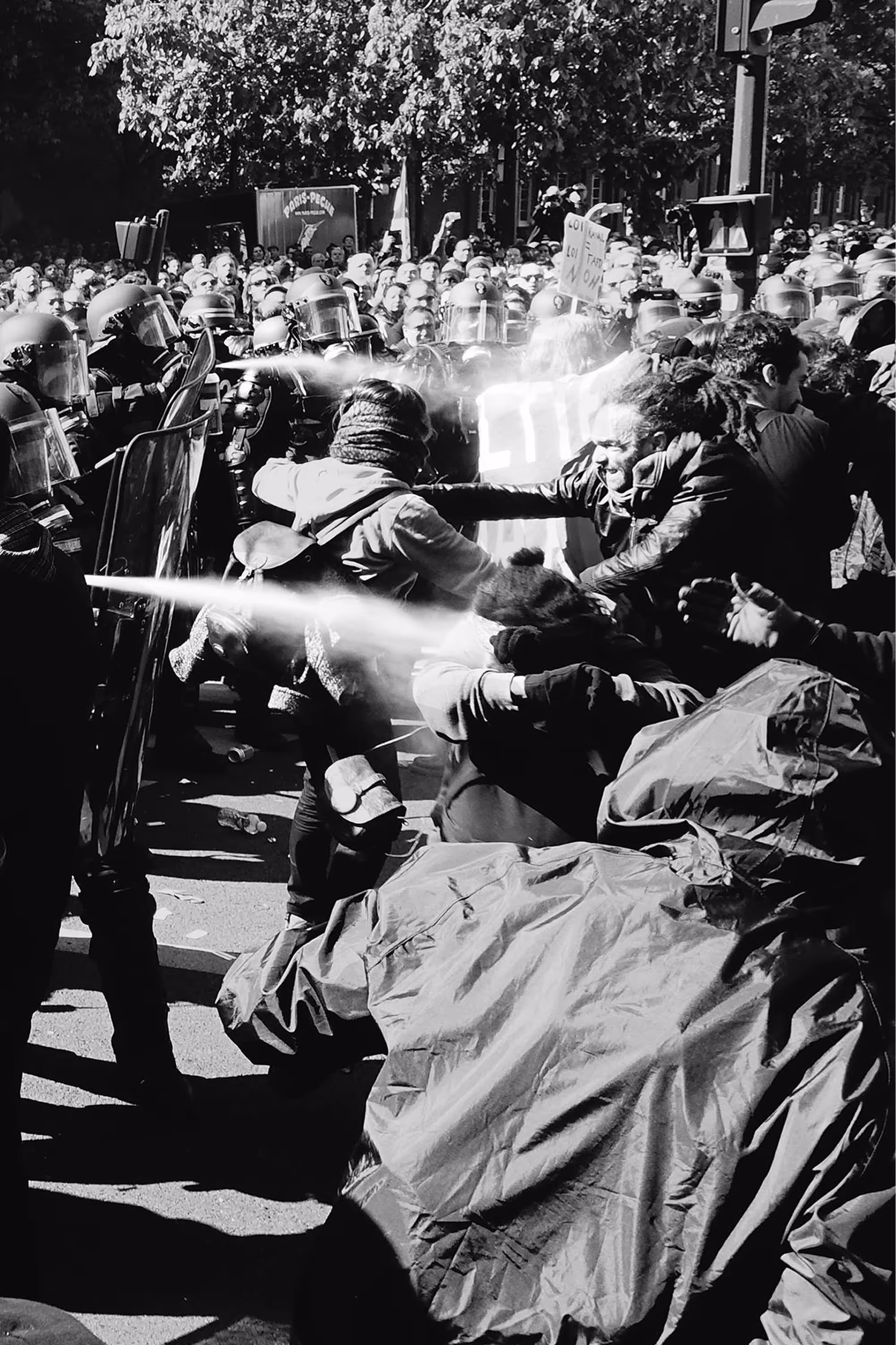Confrontation entre manifestants et policiers en tenue anti-émeute, avec utilisation de gaz lacrymogène.